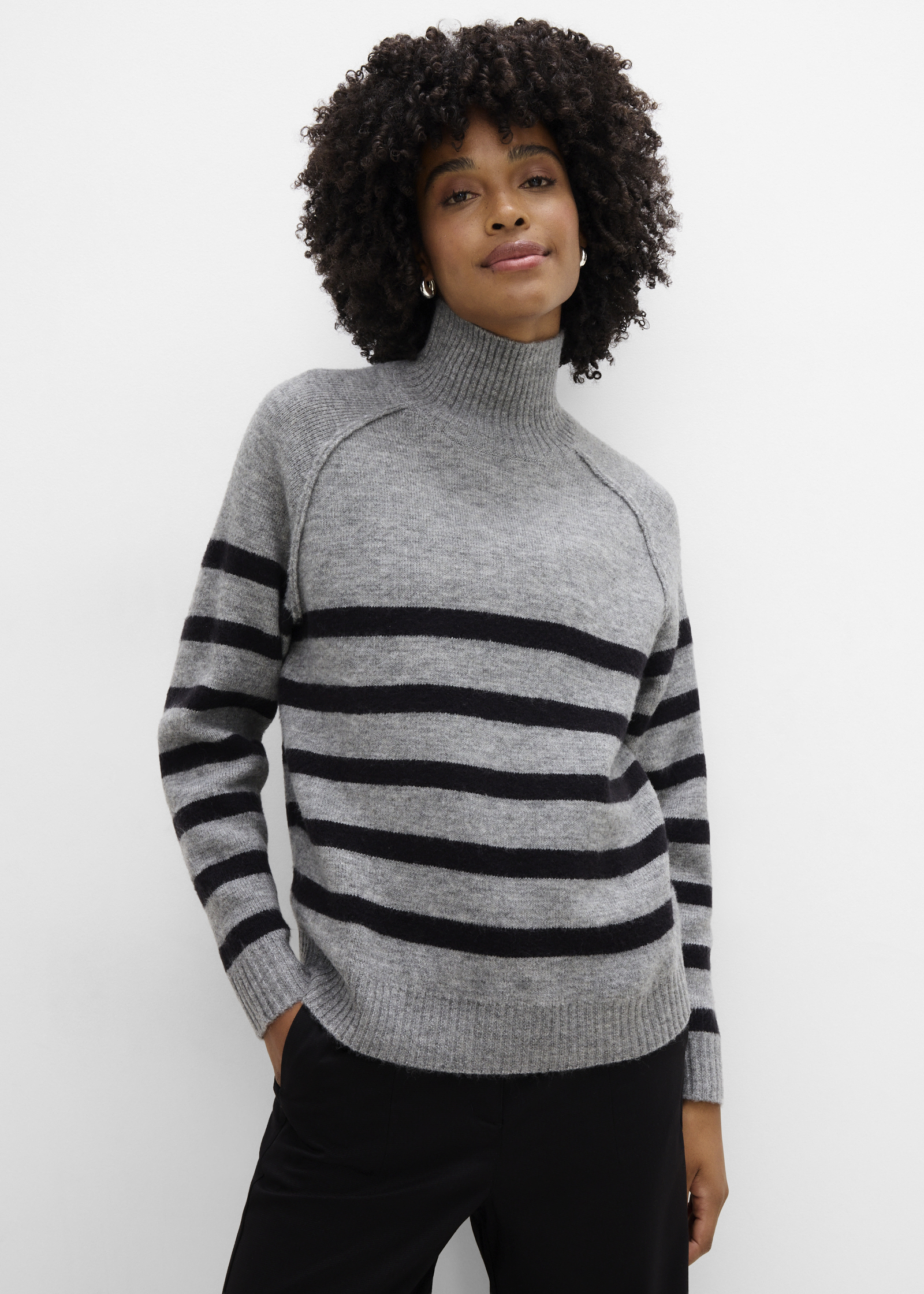 Eleganter grauer Rollkragenpullover mit schwarzen Streifen und schlichte schwarze Hose.