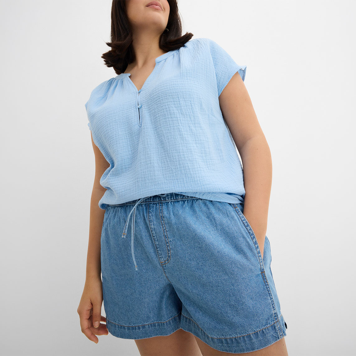 Hellblaues ärmelloses Oberteil mit Reißverschluss und lockere Jeans-Shorts in entspanntem Sommerlook.