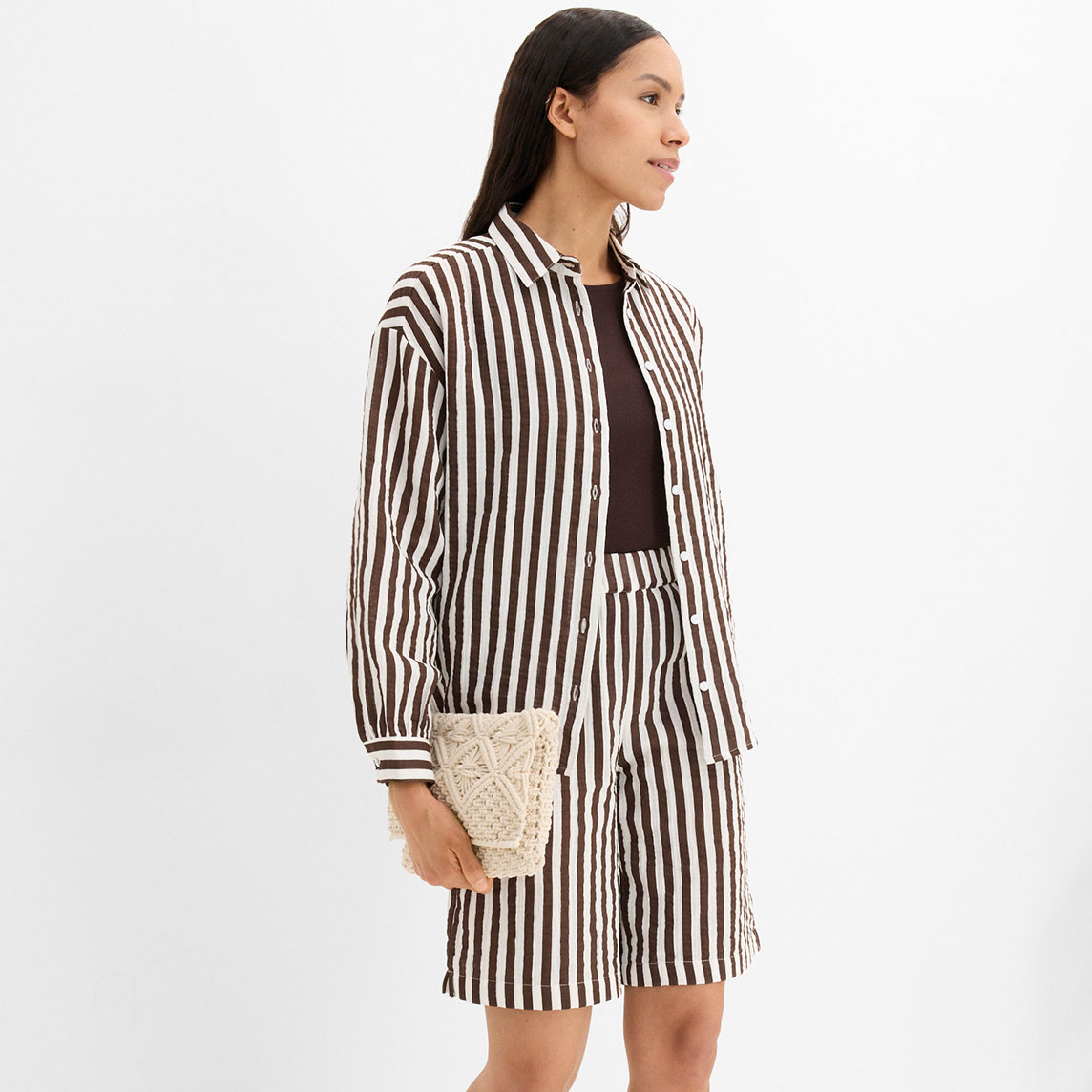 Leichtes braun-weiß gestreiftes Hemd mit passende kurzer Hose und geflochtener Clutch.