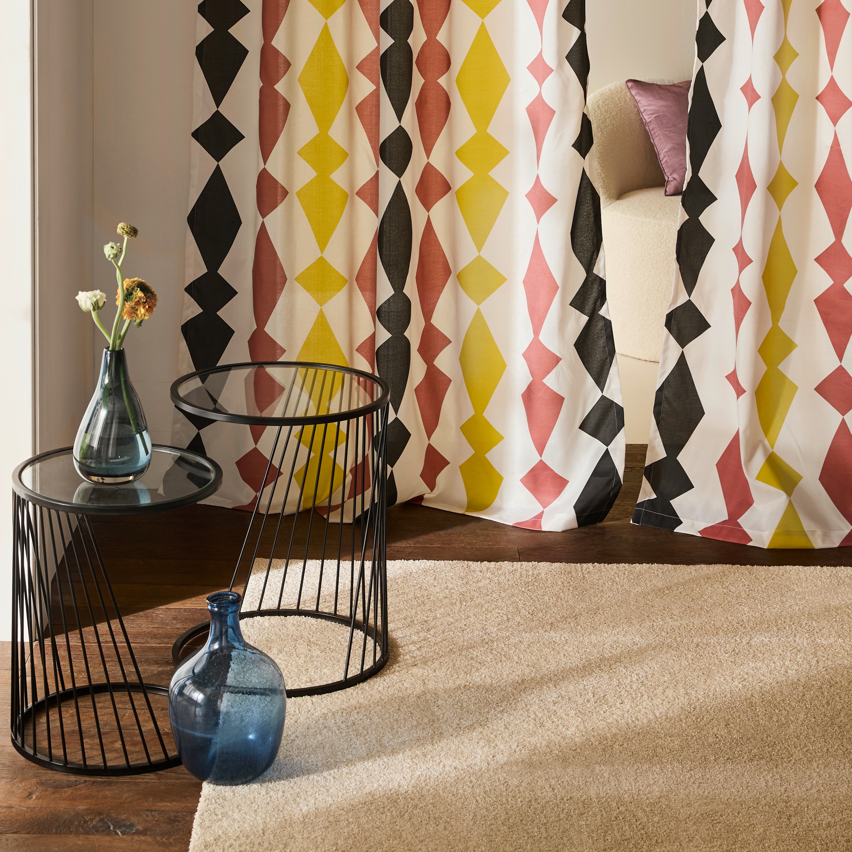 Bunte geometrische Vorhänge mit Rauten-Muster in gelb, rosa und schwarz schmücken das Wohnzimmer.