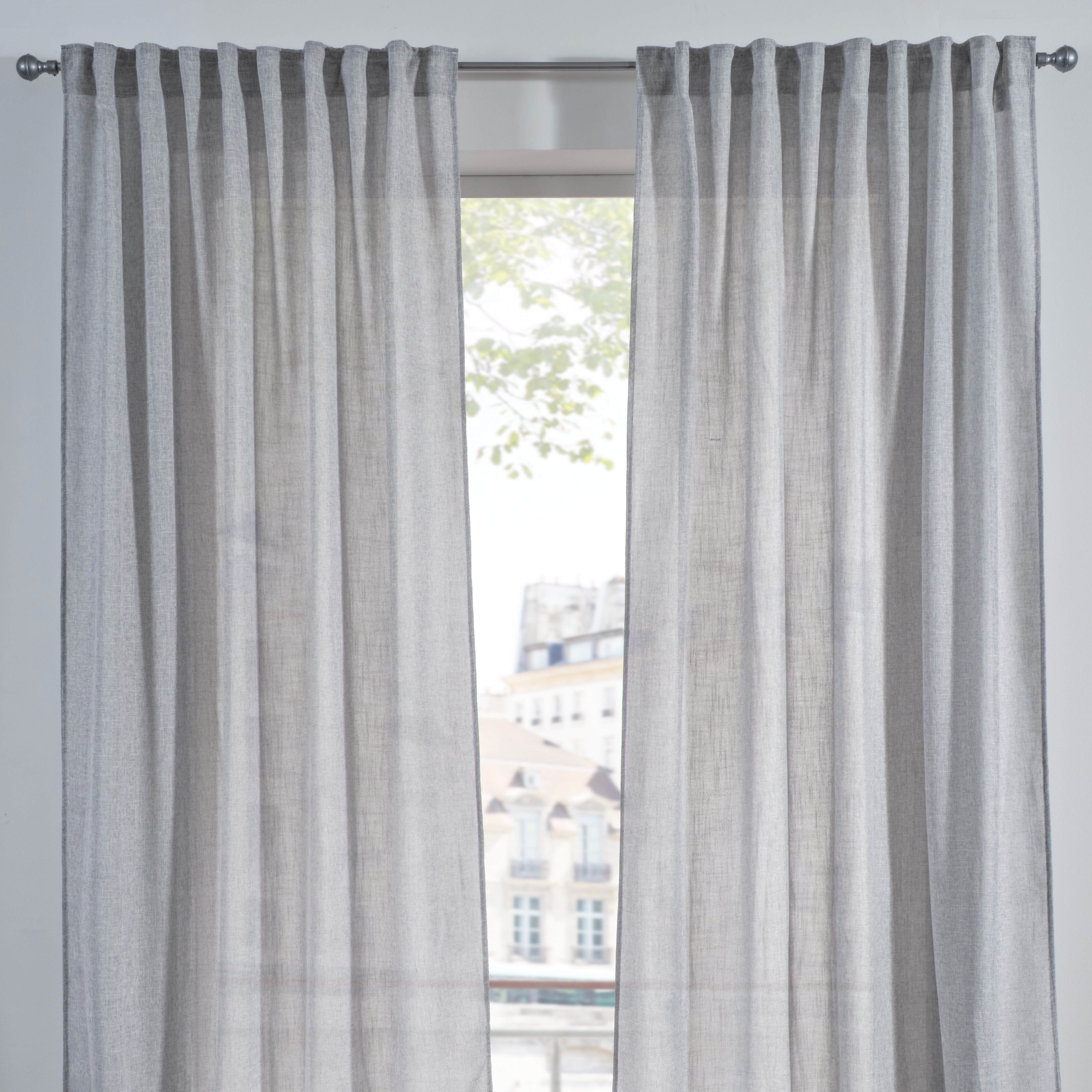 Hellgraue, luftige Vorhänge aus leichtem Stoff schmücken das Fenster.