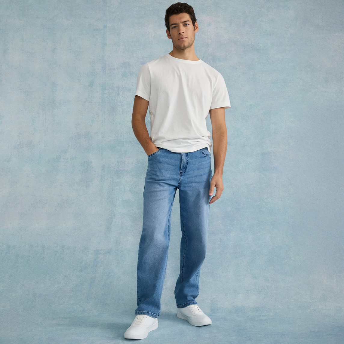 Weißes T-Shirt, blaue Loose Fit Jeans und weißen Sneakers. 