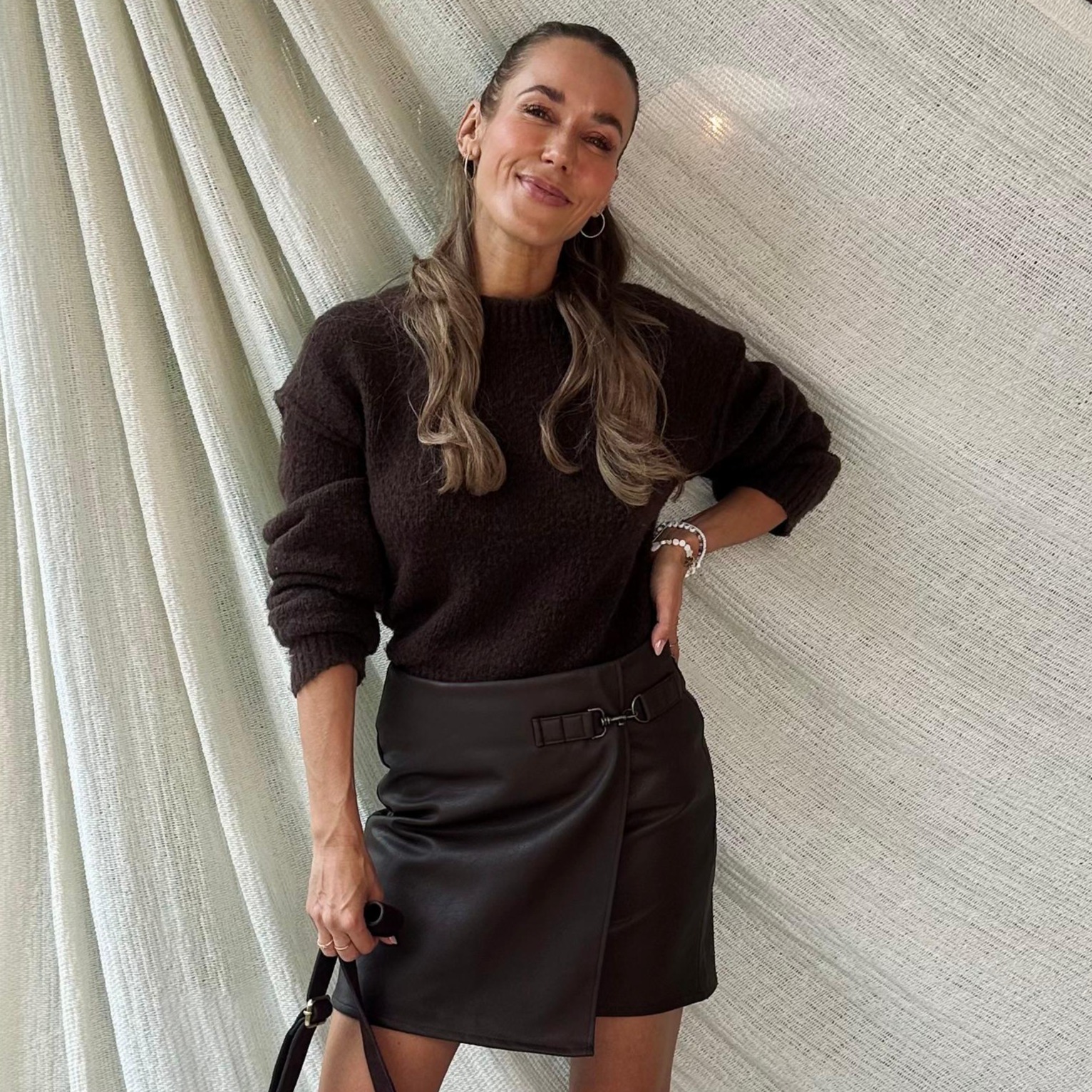 Annemarie Carpendale trägt einen brauen Pullover und brauen Rock.