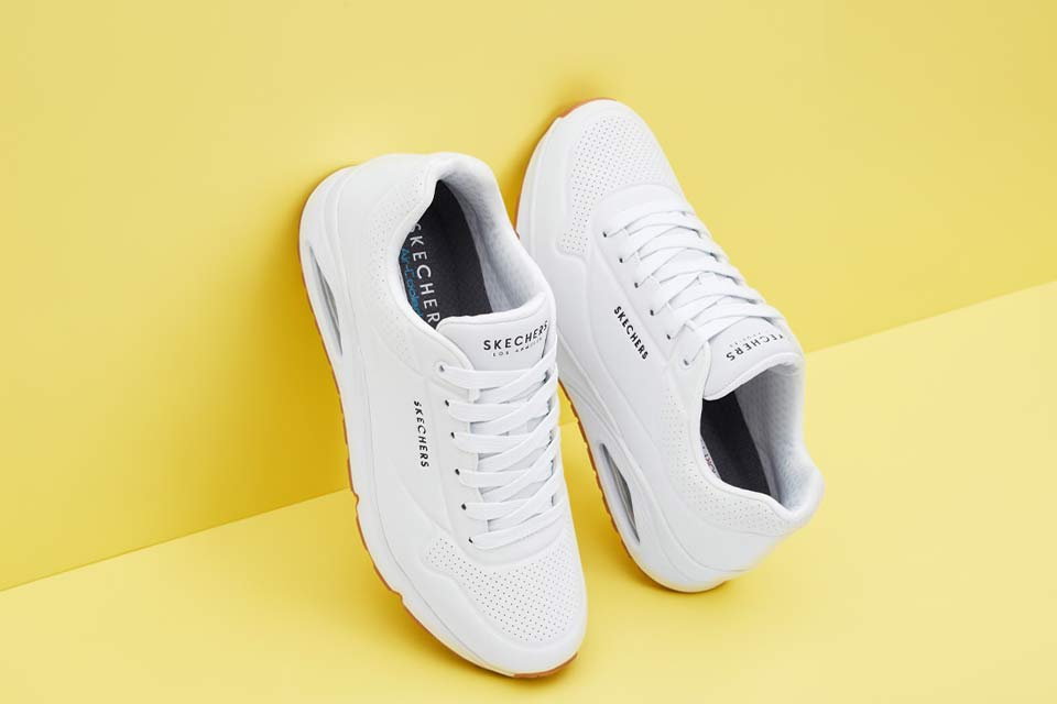Weiße Sneaker mit schwarzen Details und Schnürung.