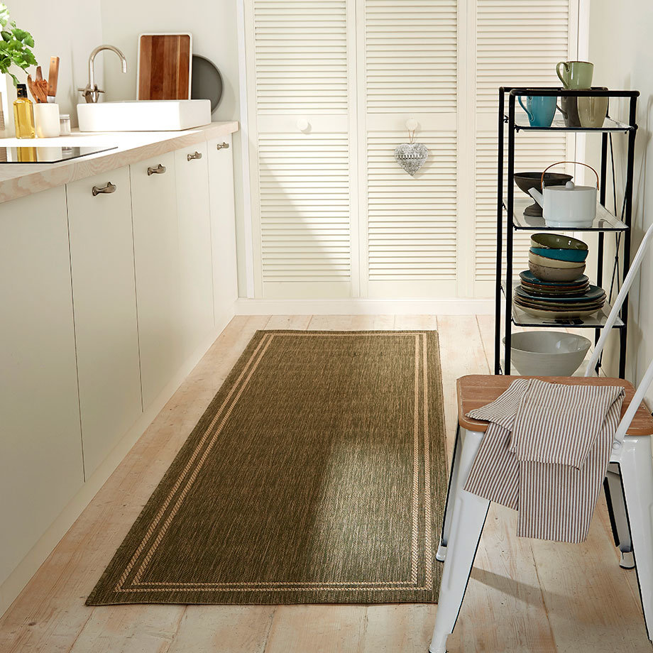 Ein gestreiftes Handtuch hängt über einem weißen Stuhl in der hellen Küche.