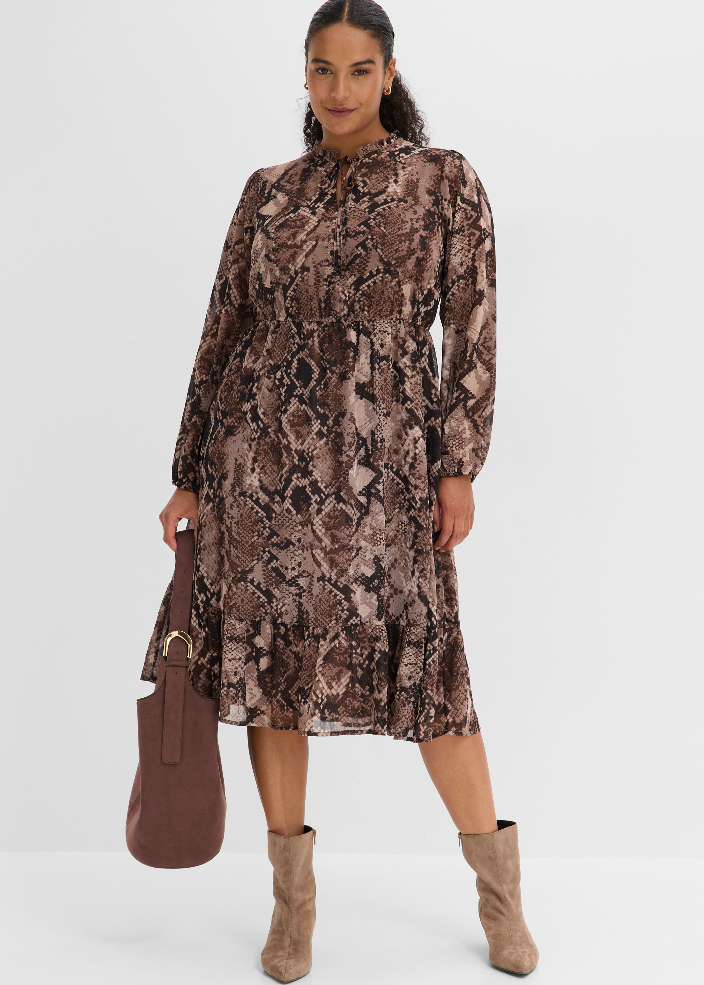 Elegantes Schlangenprint-Kleid mit langen Ärmeln, kombiniert mit passenden Stiefeln und Handtasche.