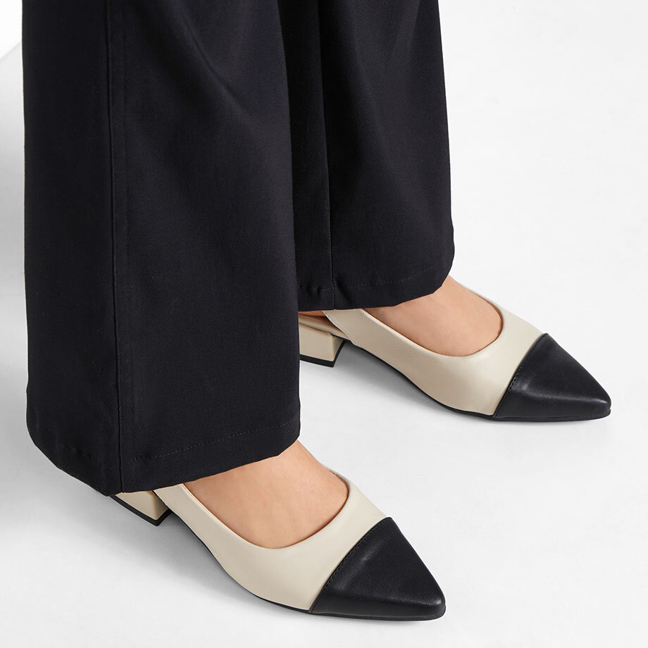 Elegante zweifarbige Pumps mit spitzer Kappe ergänzen perfekt die weite schwarze Hose.