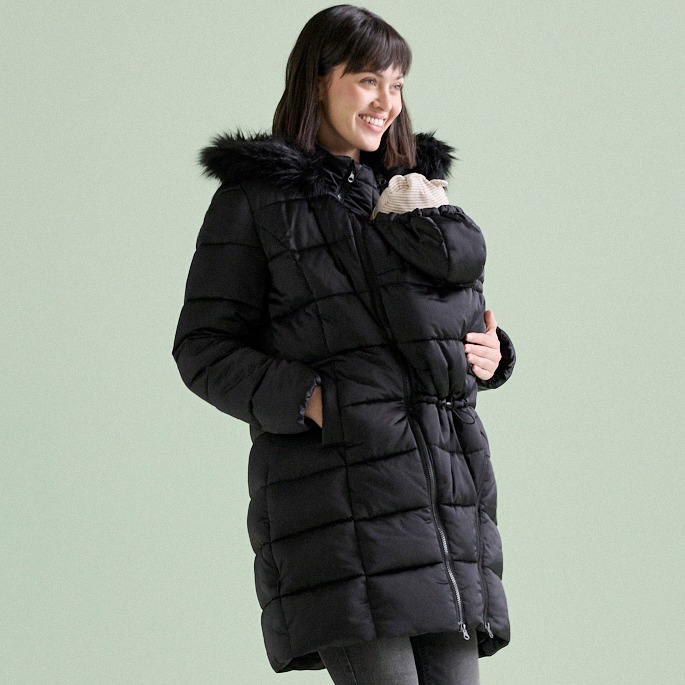 Warmer schwarzer Mantel über beiger Fleecejacke und dunkler Hose.