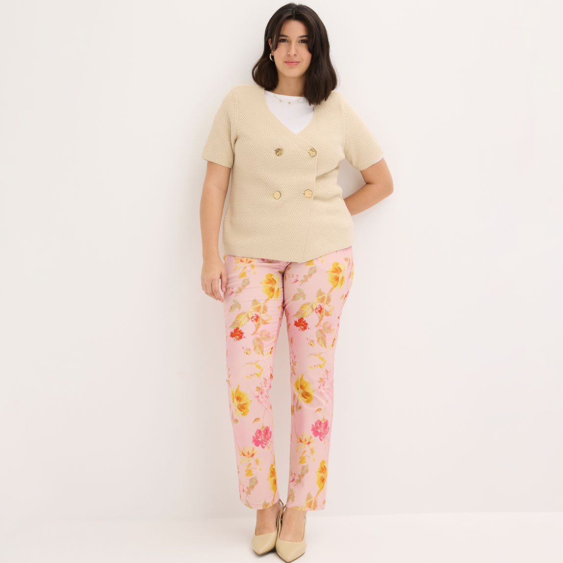 Beige Strickjacke mit Knöpfen kombiniert mit bunten Blumenhosen in Rosa und Gelb.