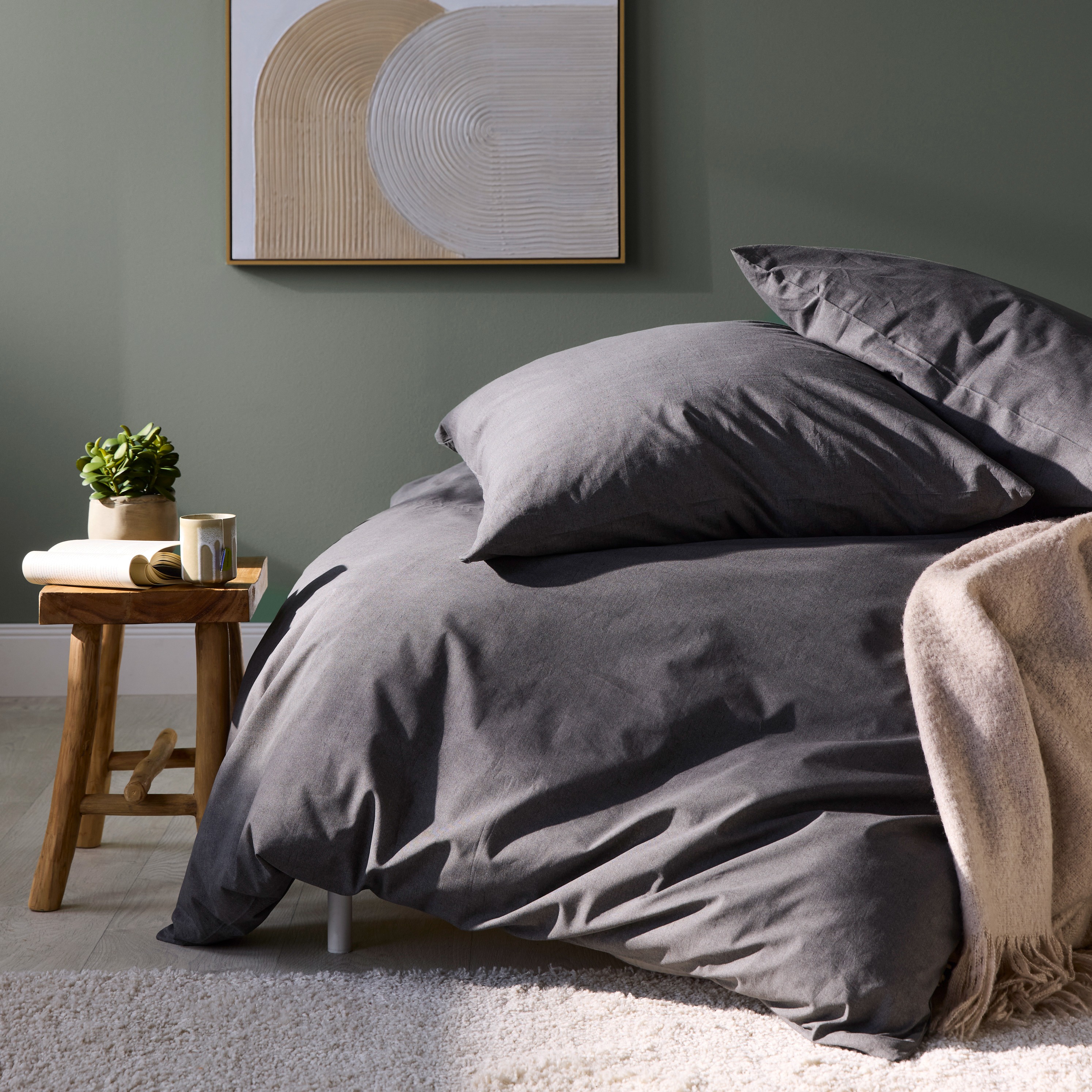 Gemütliche graue Bettwäsche lädt zum Entspannen ein. Warme Decke und weiche Kissen versprechen Behaglichkeit.