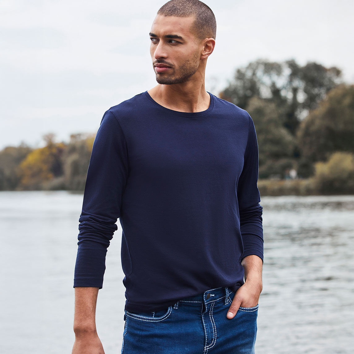 Blaues Langarmshirt und dunkle Jeans.