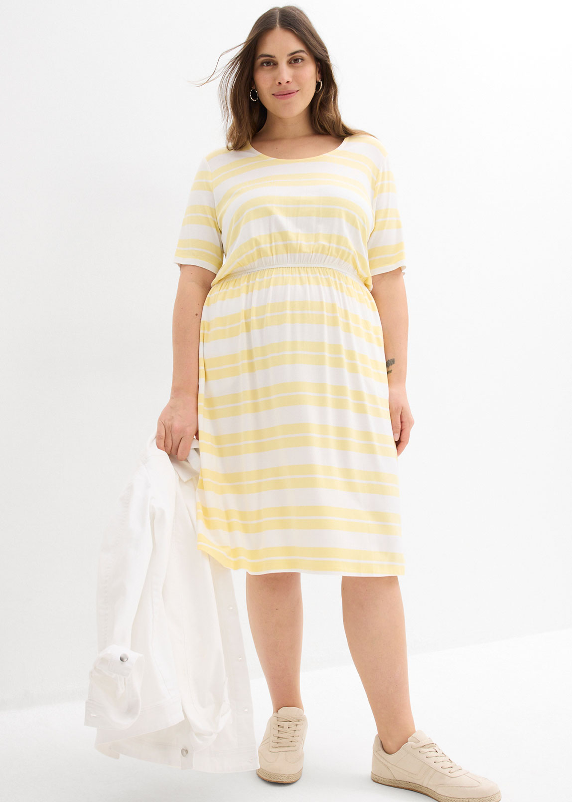 Hellgelb gestreiftes Shirtkleid und beige Sneaker.