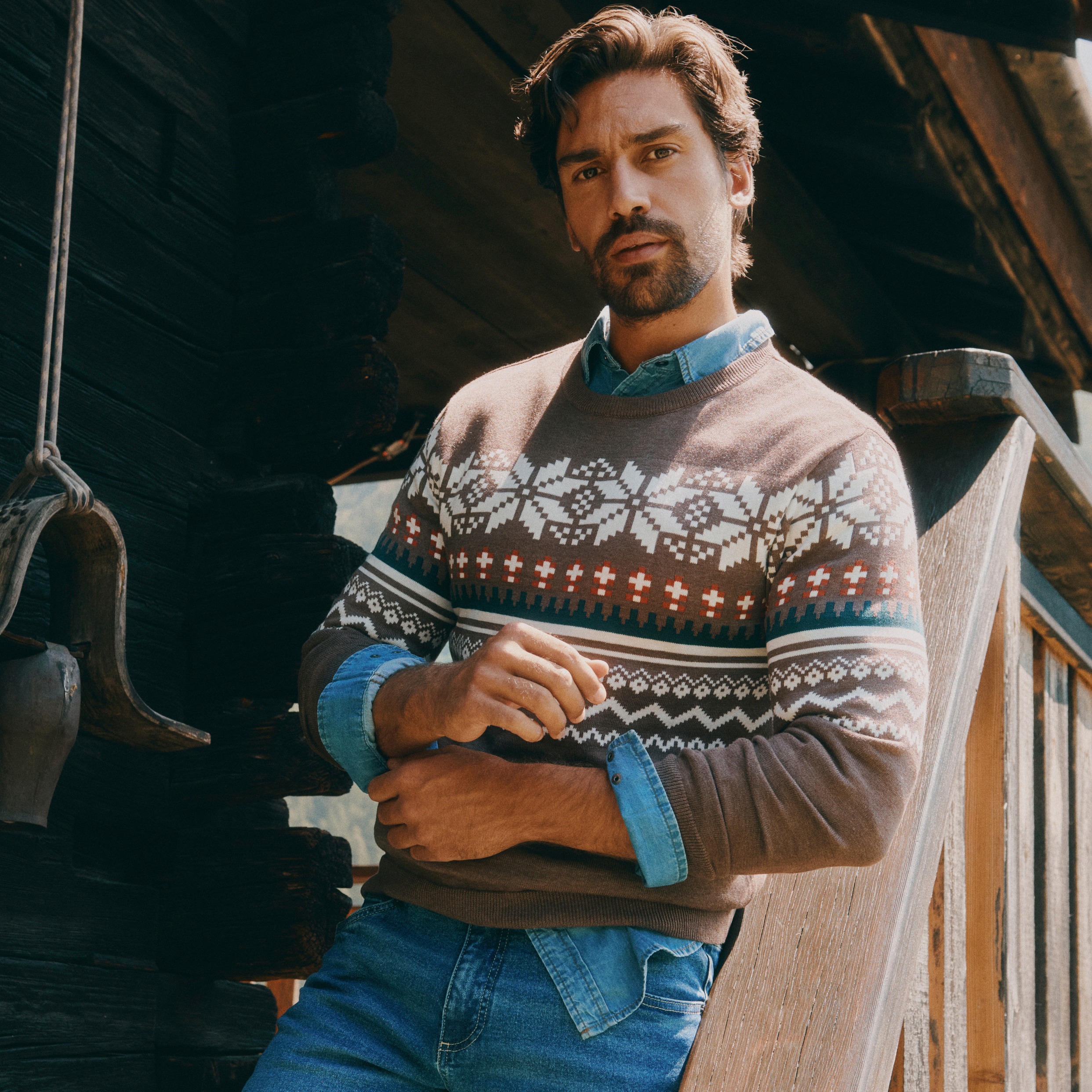 Norwegerpullover mit Schneeflockenmuster über Jeanshemd und Jeans.