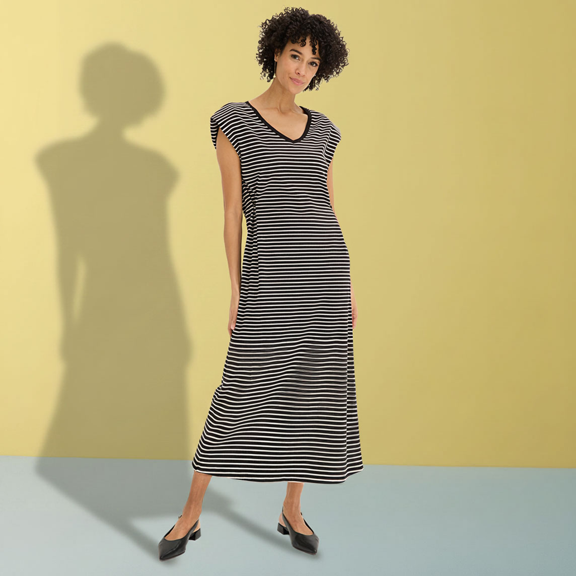 Elegantes schwarz-weiß gestreiftes Maxikleid mit V-Ausschnitt und schwarzen Ballerinas.