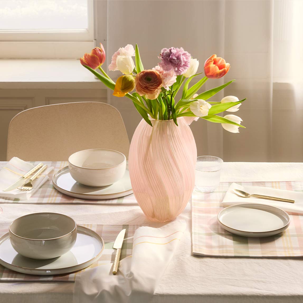 Frühlingshaft geschmückter Tisch mit Vase und Geschirr. 