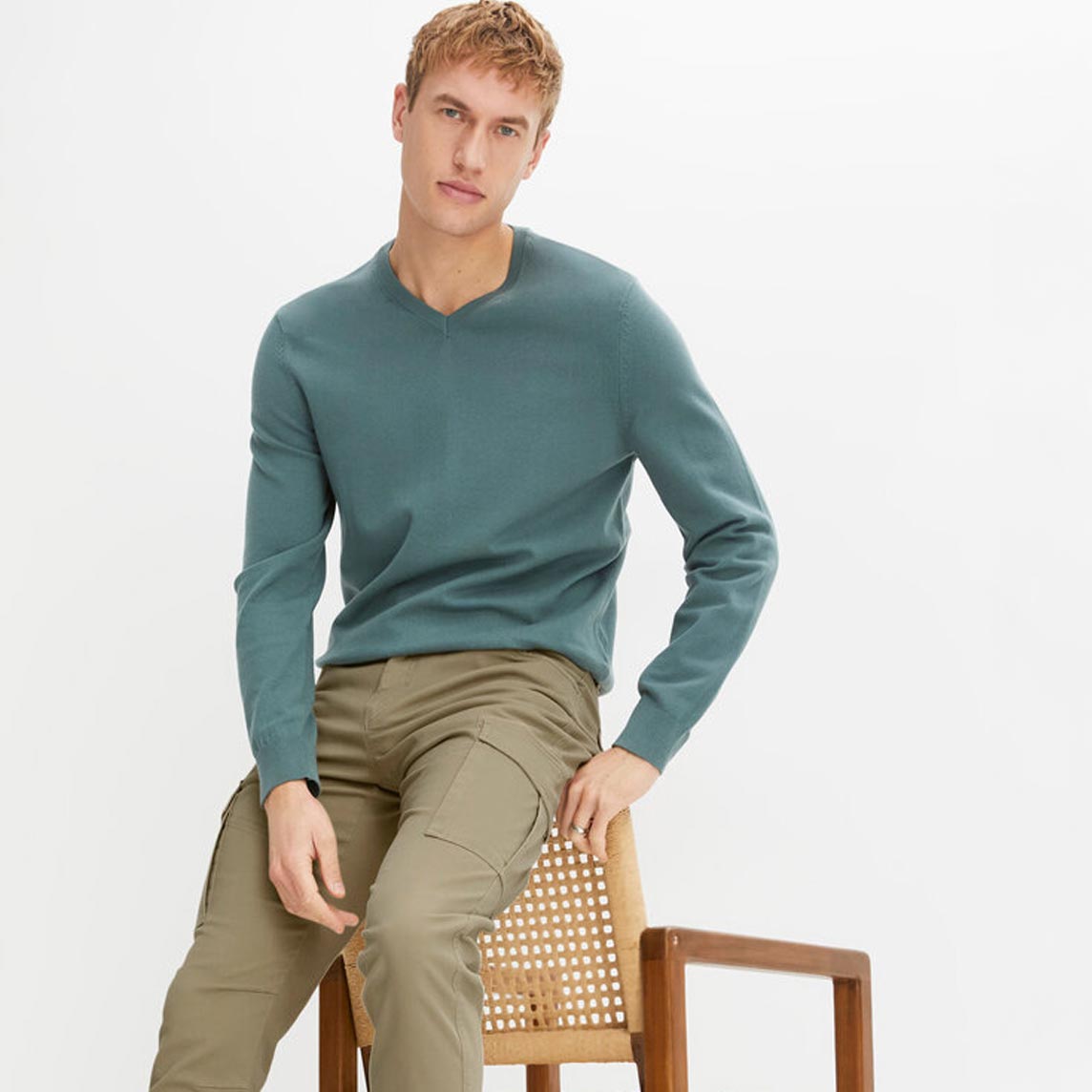 Grüner Feinstrickpullover aus weichem Baumwollmix und beiger Hose. 