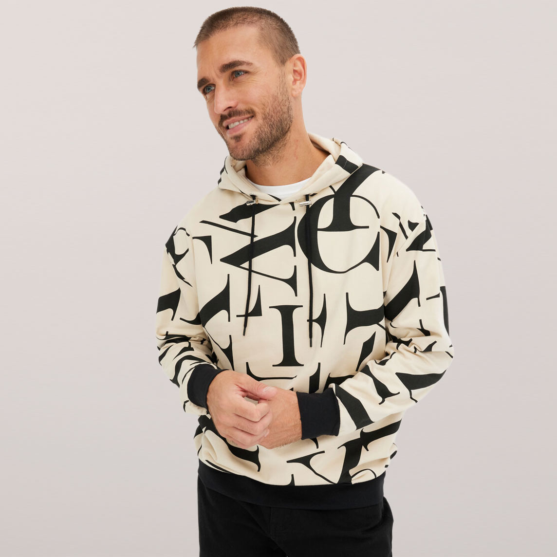 Sweatshirt mit schwarz-weißem geometrischem Muster über schwarzer Hose.