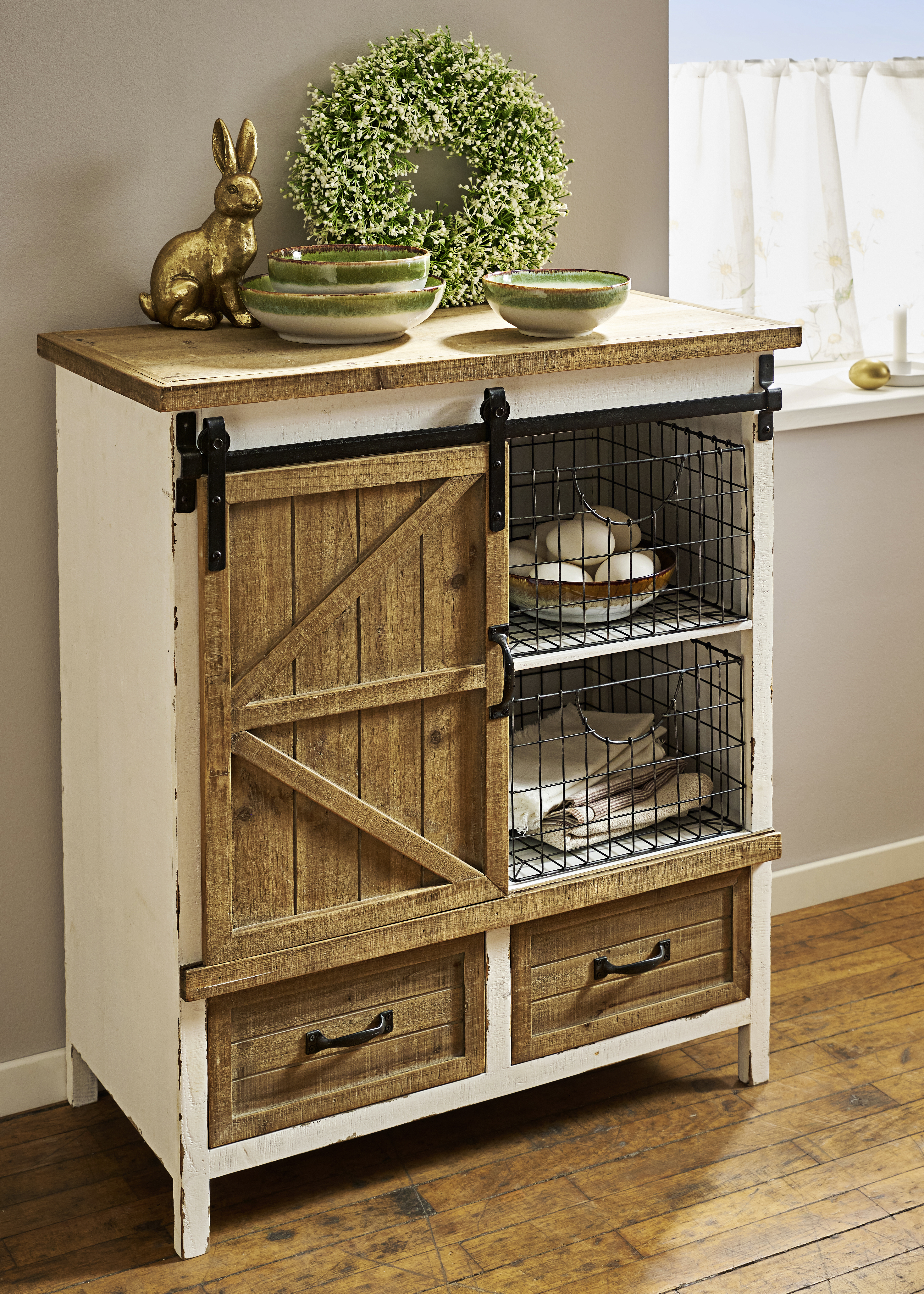 Rustikaler Holzschrank dekoriert mit Frühlingskranz und goldenem Hasen.