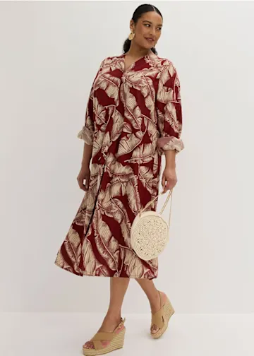 Midi-Kleid mit botanischem Druck in Rot-Beige, kombiniert mit geflochtener Handtasche und Keilabsätzen.