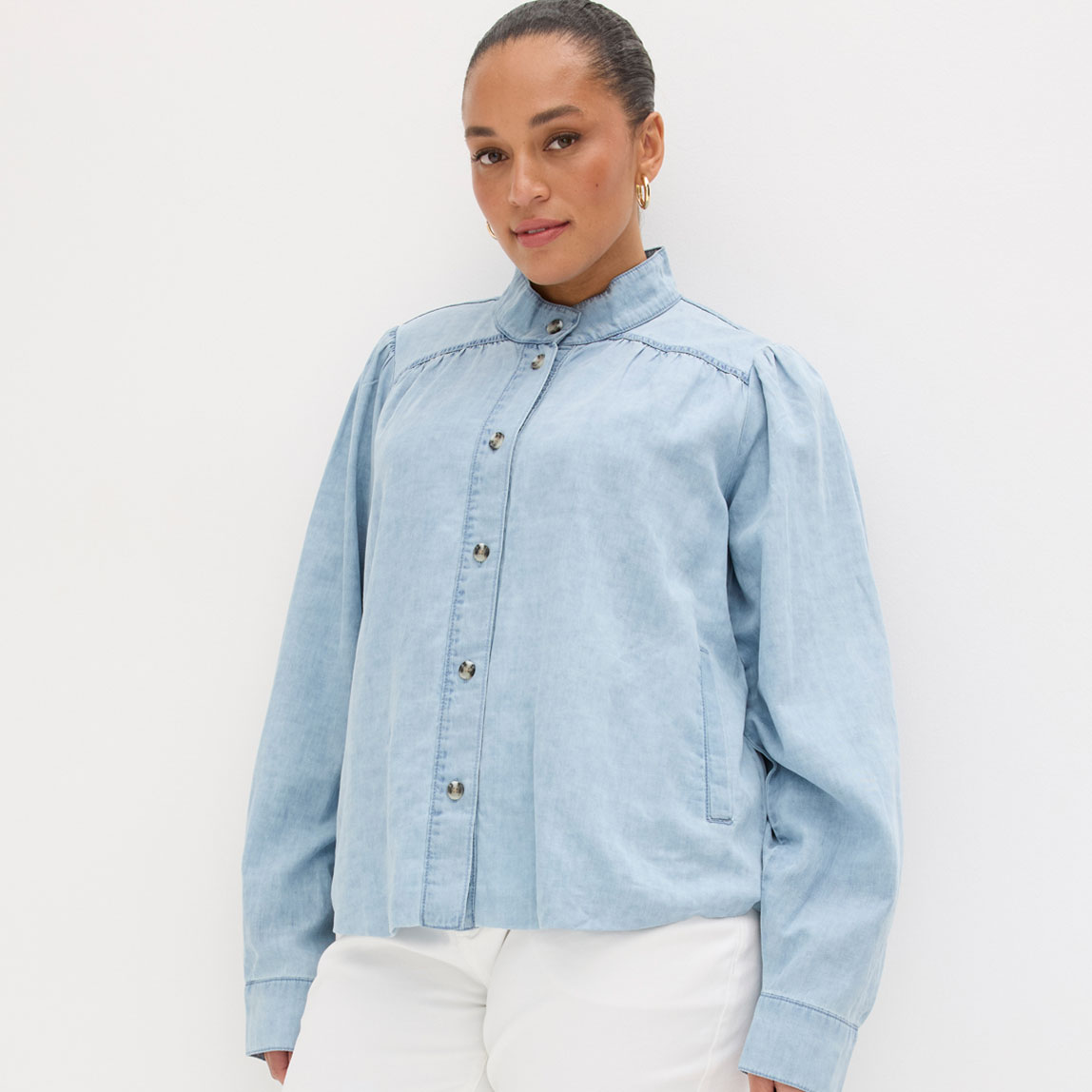 Kurze hellblaue Jacke mit Knopfleiste wird zu weißer Hose getragen.