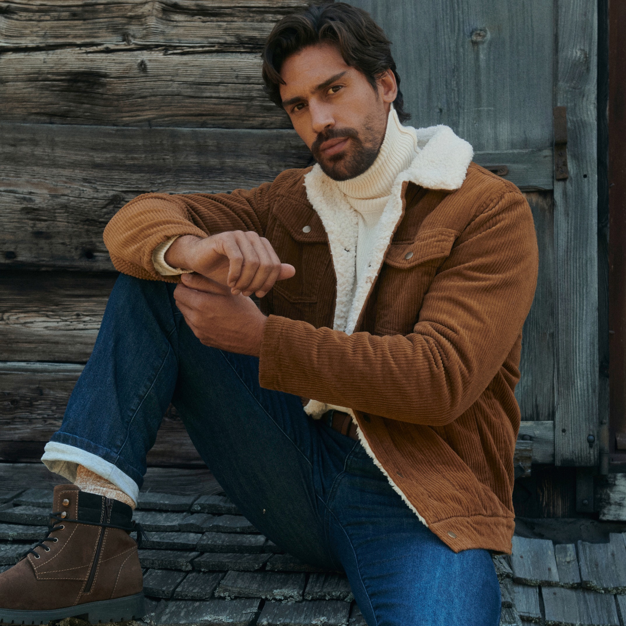 Braune Cordjacke mit Teddyfutter, weißer Rollkragenpullover, Jeans und winterliche Boots.