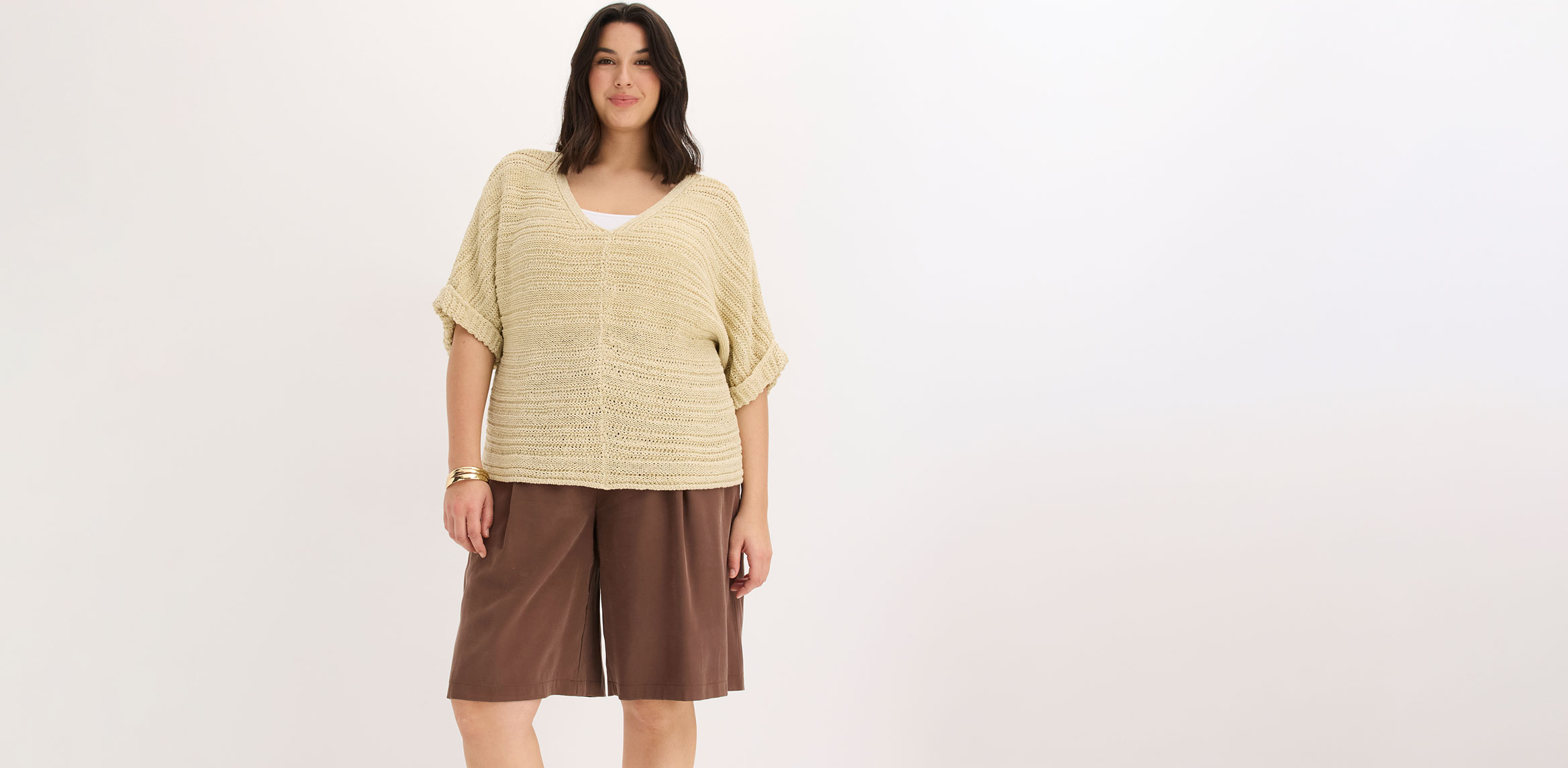 Frau trägt beiges Strickoberteil und braune weite Shorts.
