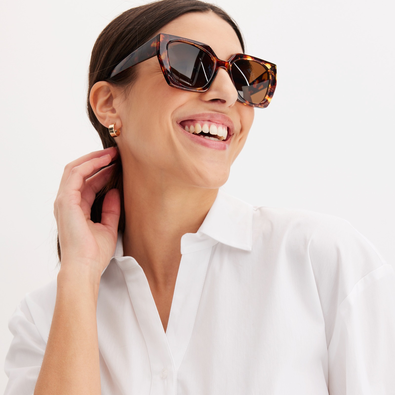 Frau trägt weiße Bluse und stylische Sonnenbrille.