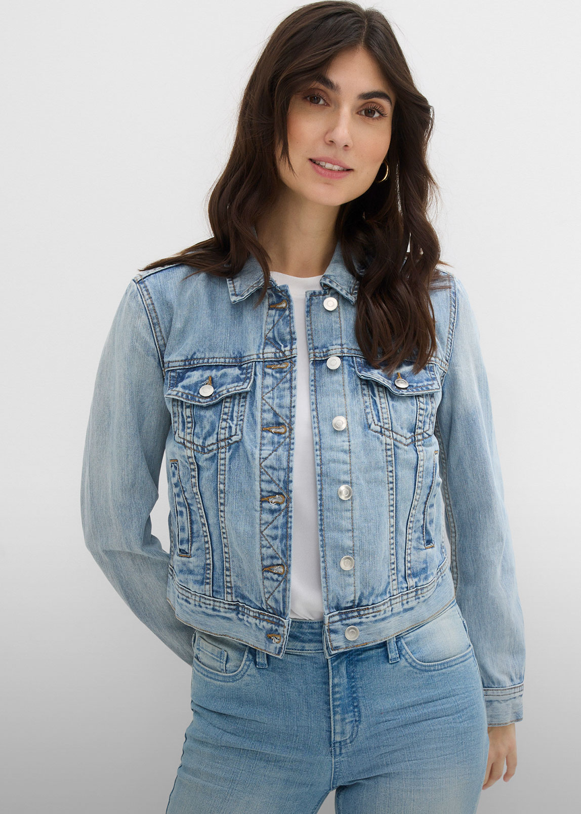 Modische helle Jeansjacke über weißem Shirt, kombiniert mit passender Jeans.