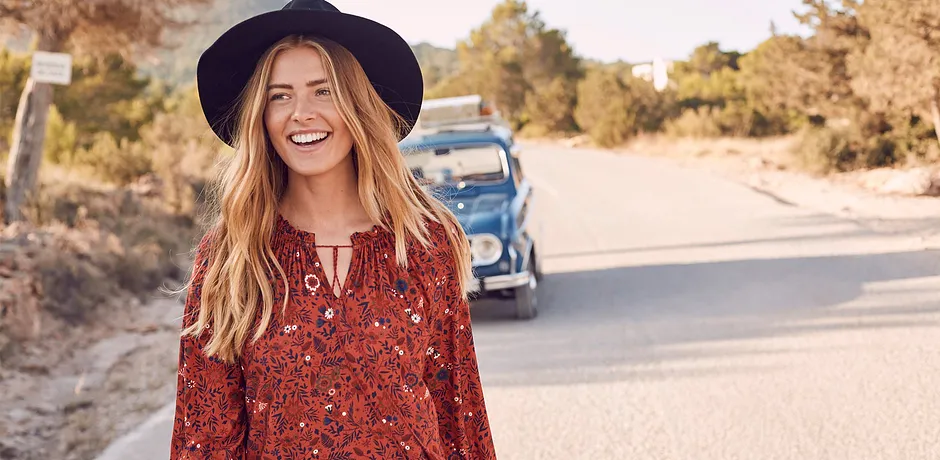 Luftiges rotes Kleid mit Blumenmuster, passend zum Sommertag. Dazu ein dunkler Hut als stilvoller Akzent.
