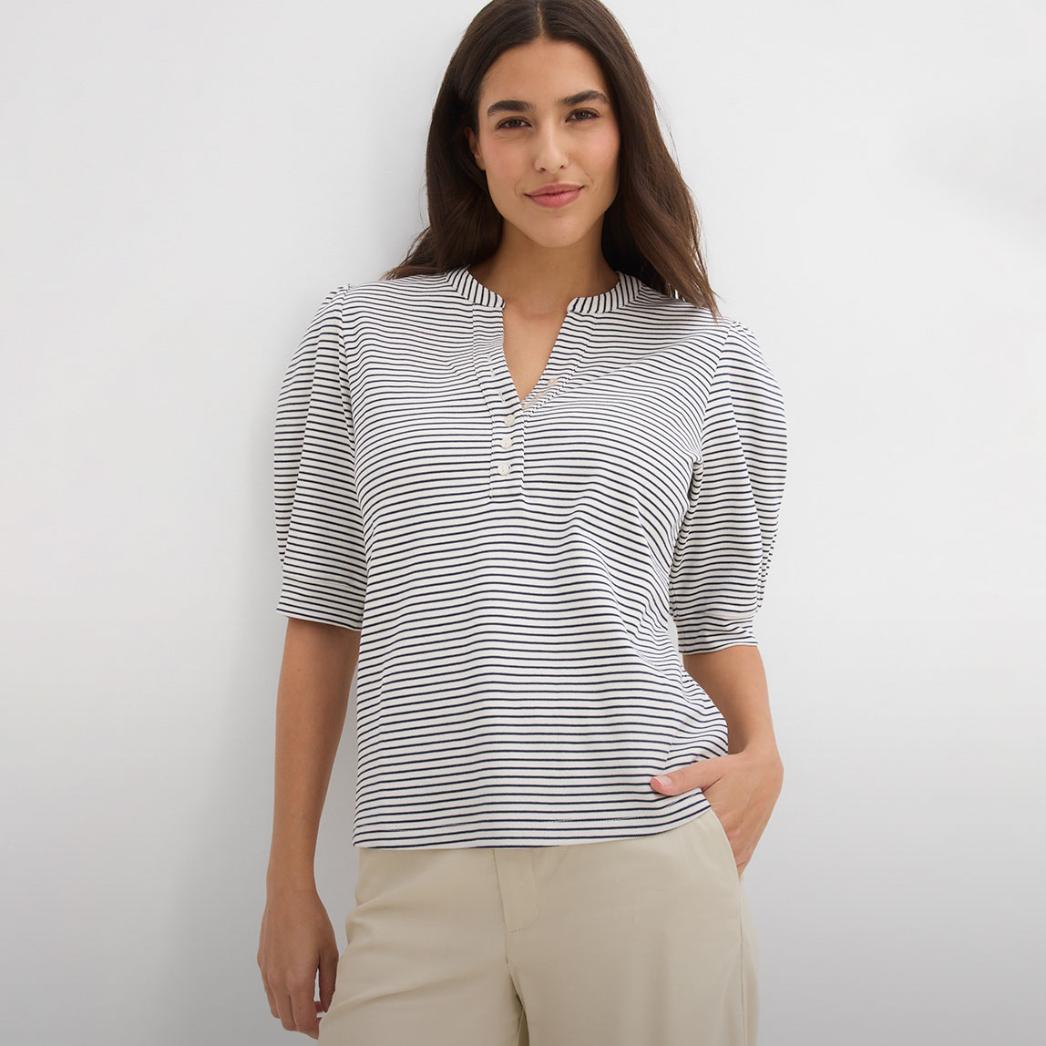 Gestreiftes Shirt mit Puffärmeln und Knopfleiste, kombiniert mit heller Hose.