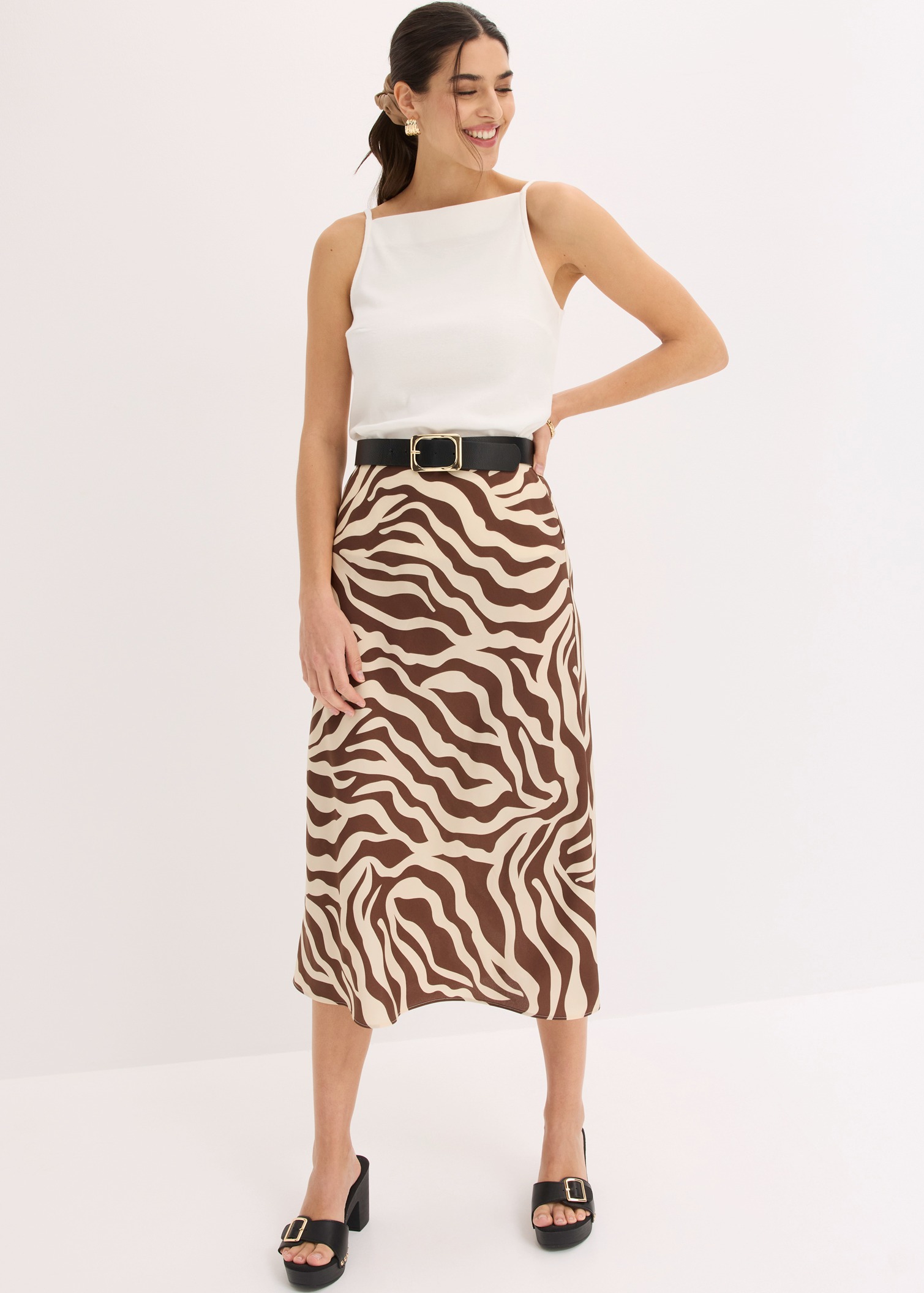 Elegantes weißes Top kombiniert mit auffälligem Zebrastreifenrock, schwarzem Gürtel und Plateausandalen.