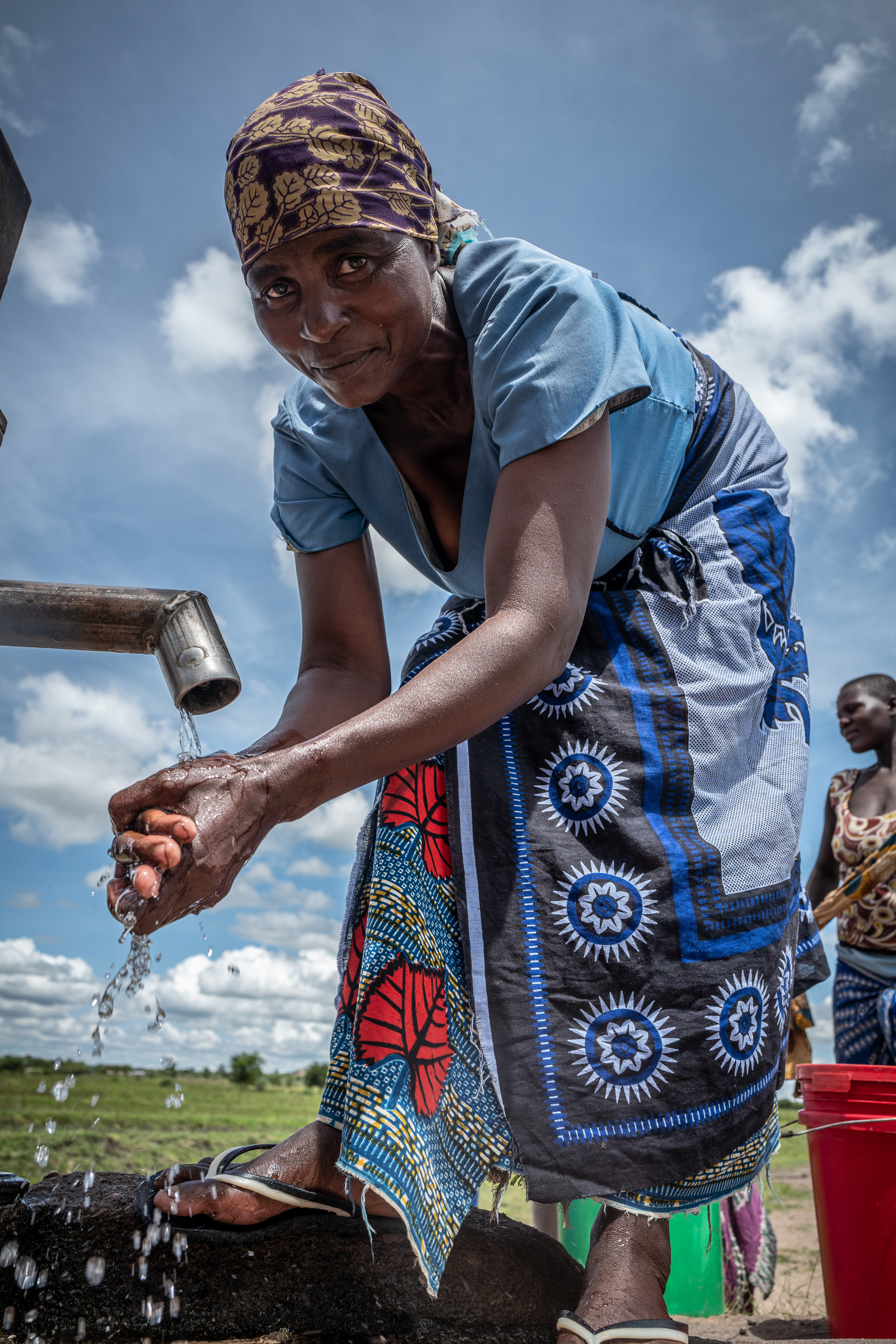 Buntes Kopftuch und traditioneller Rock mit Blumenmuster. Hellblaue Bluse betont den sommerlichen Look.