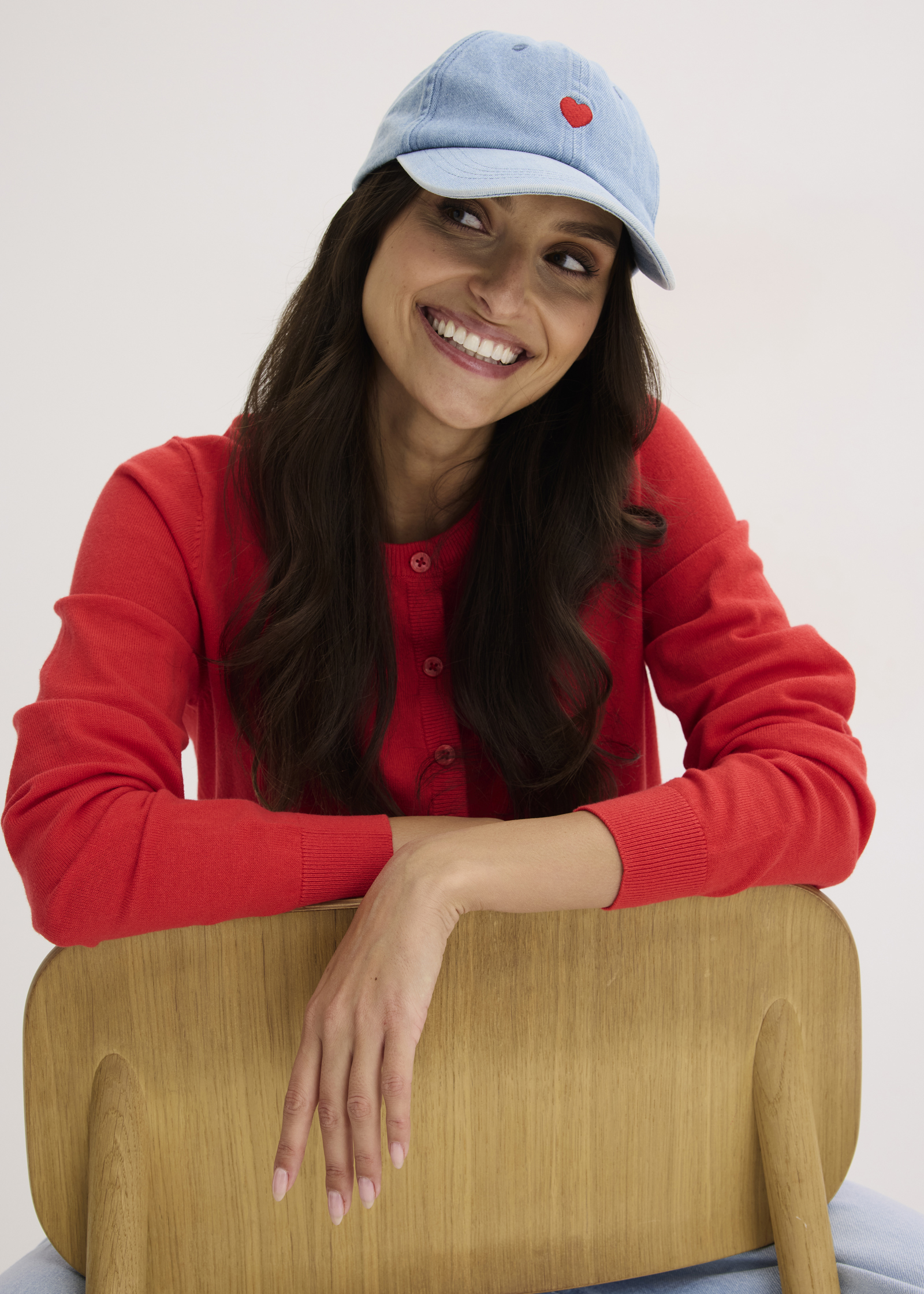 Lässiger Look mit rotem Pullover und hellblauer Baseball-Cap mit rotem Herz.