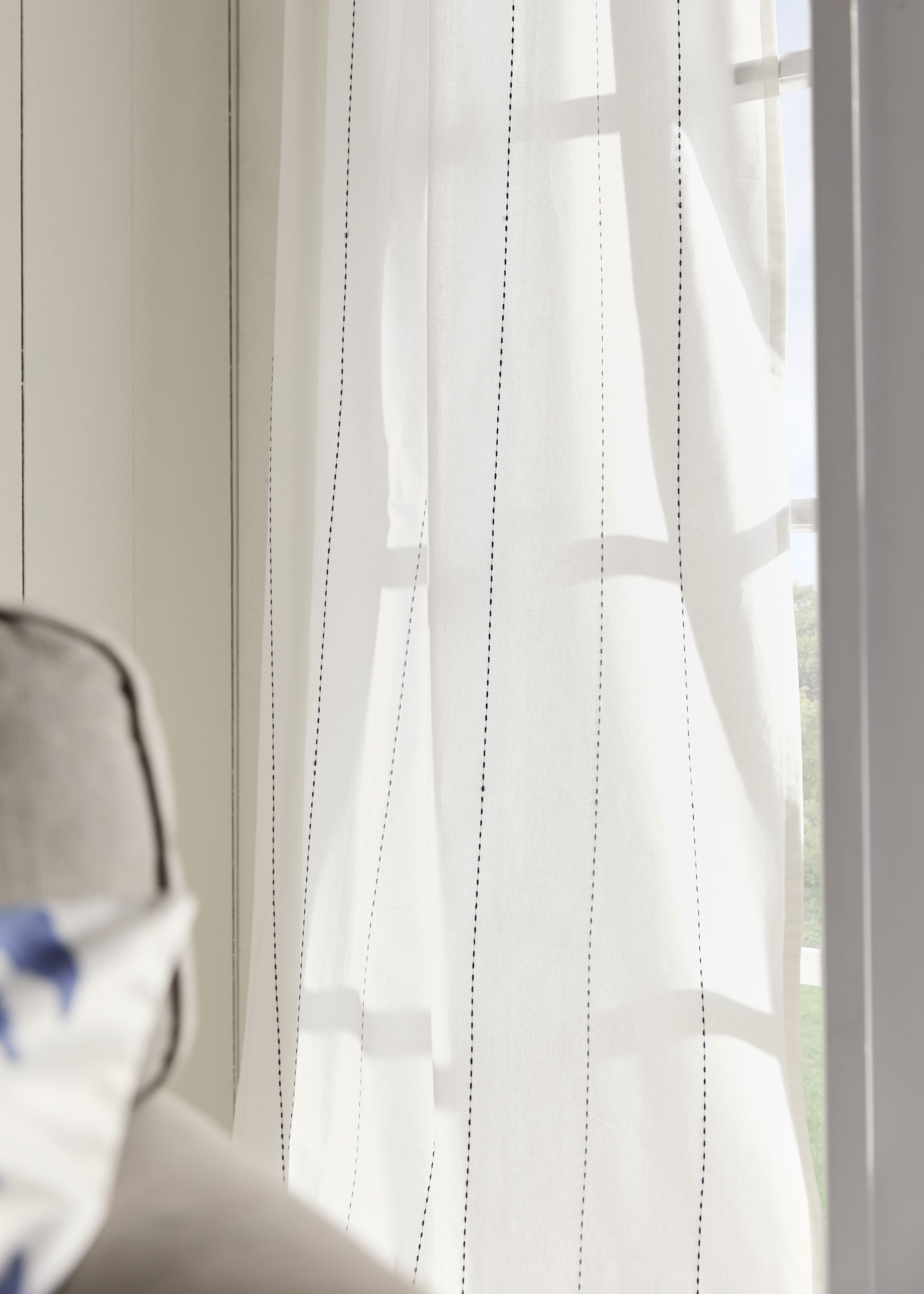 Leichte, transparente Vorhänge lassen sanftes Licht durch das Fenster ins Zimmer strömen.