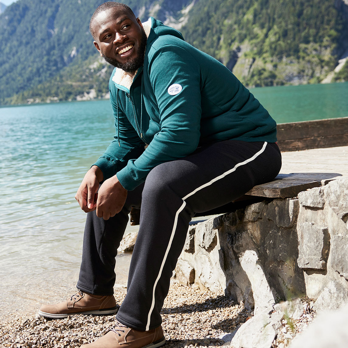 Grüne Thermo-Sweatjacke und graue Jogginghose.