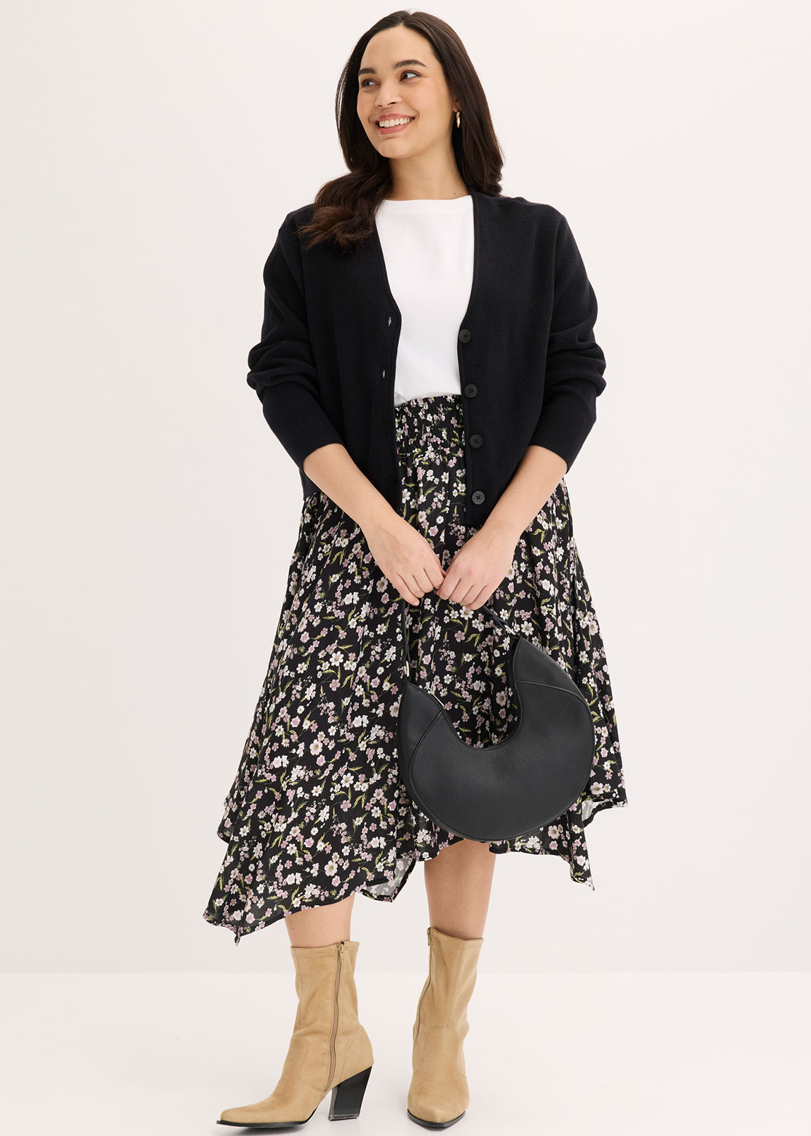 Schwarze Strickjacke, weißes Shirt und schwarz-weiß gemusterter Midirock.