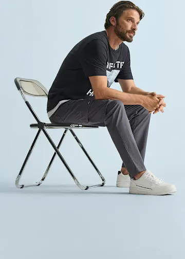 Schwarzes T-Shirt mit Aufdruck, bequeme graue Cargohose und lässige weiße Sneaker.