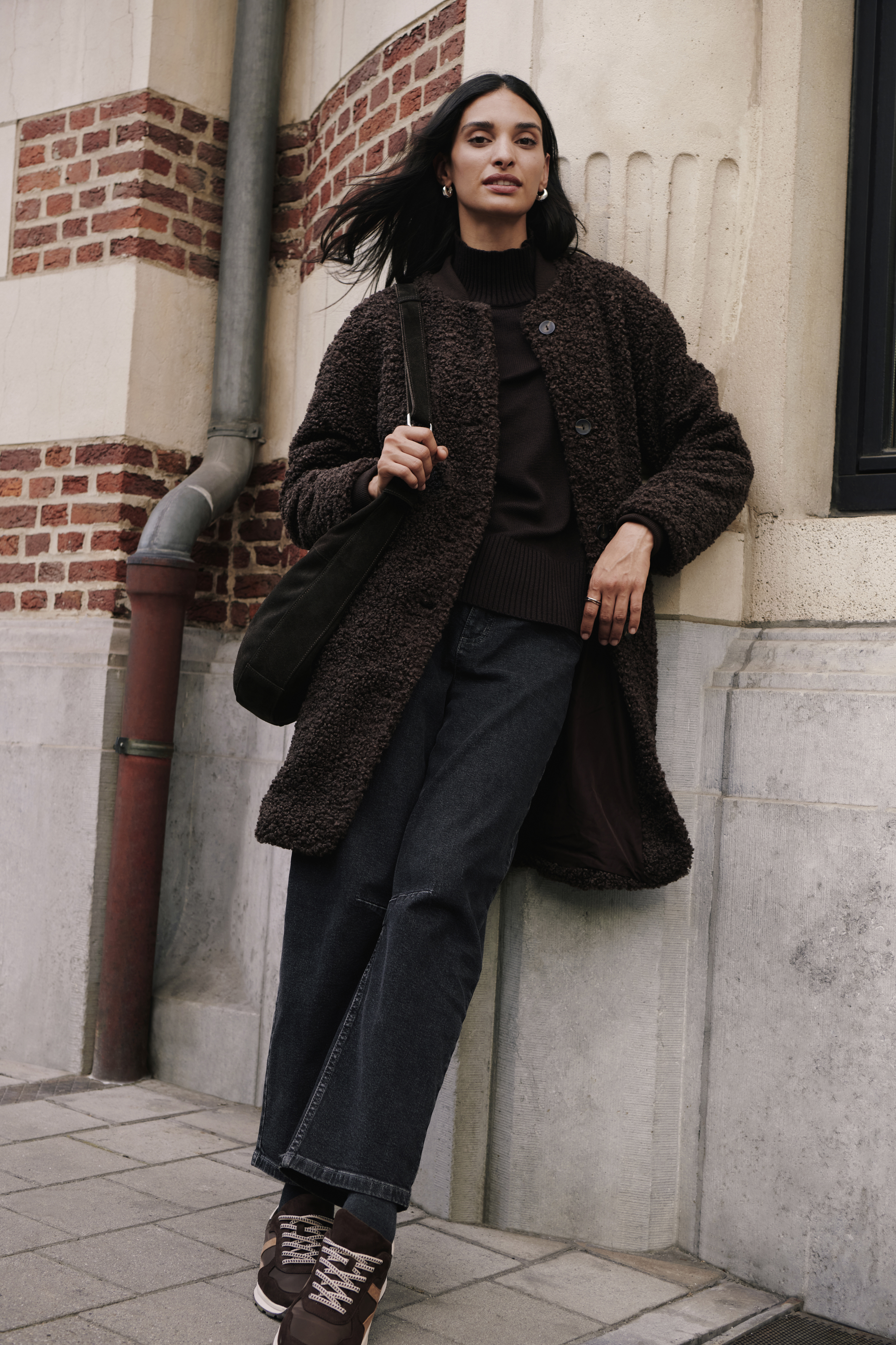 Brauner Teddymantel, Rollkragenpullover, dunkle Jeans und Sneaker bilden ein stilvolles Outfit.