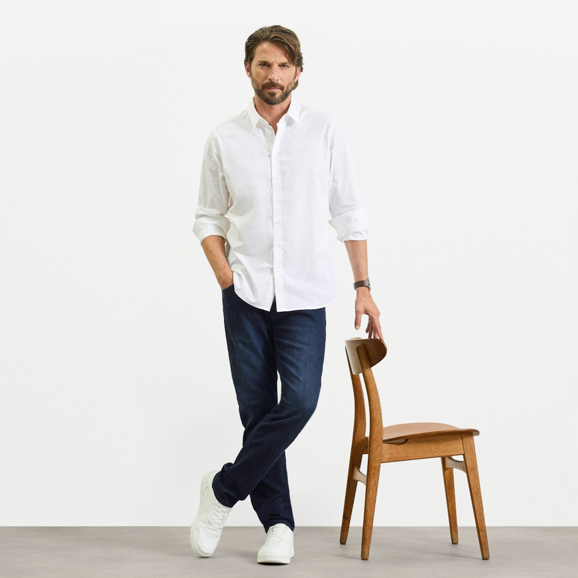 Weißes Hemd, dunkle Slim- Fit Jeans und weiße Sneaker.
