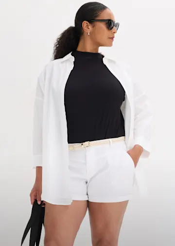 Weiße offene Hemdbluse über schwarzem Top, weiße Shorts, heller Gürtel, Sonnenbrille.