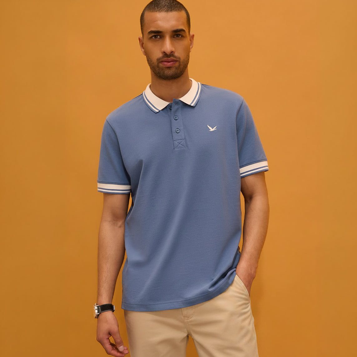 Blaues Poloshirt mit elegantem weißen Kragen und passender beiger Hose.