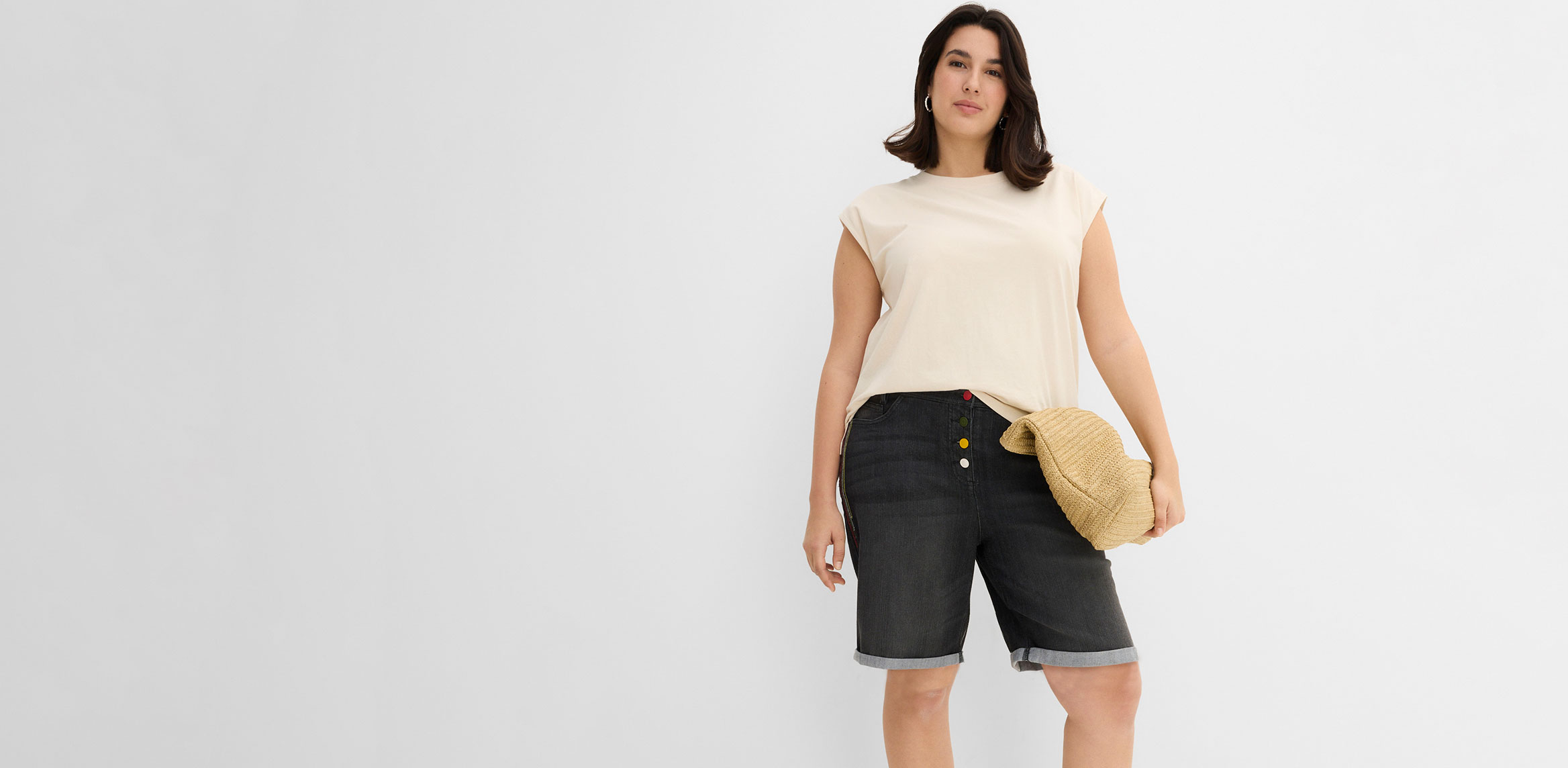 Beiges Oberteil und dunkle Jeans  Bermudas mit Krempelbeinen.
