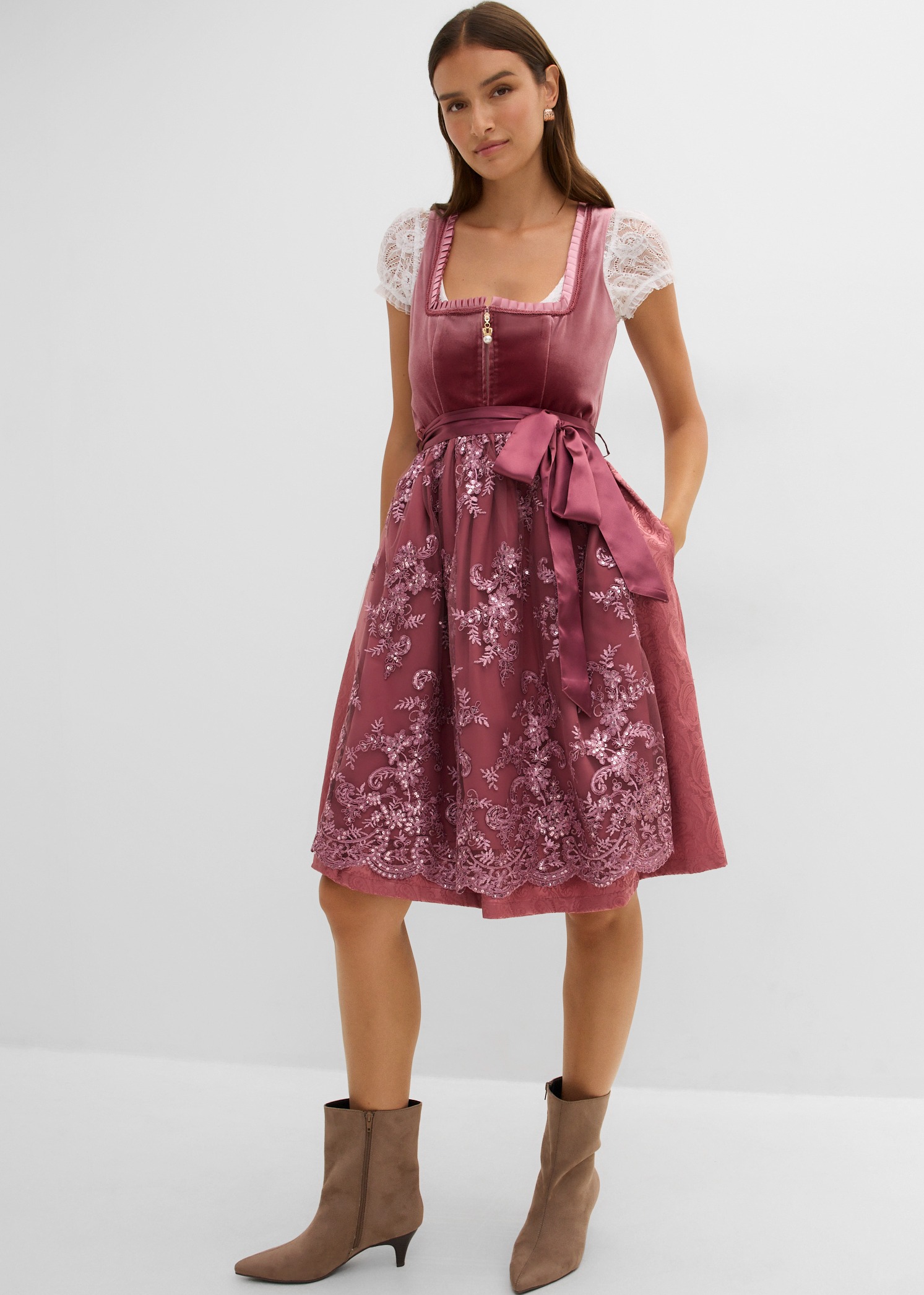 Elegantes altrosafarbenes Samtdirndl mit Spitze und passender Schürze, dazu modische Stiefeletten.