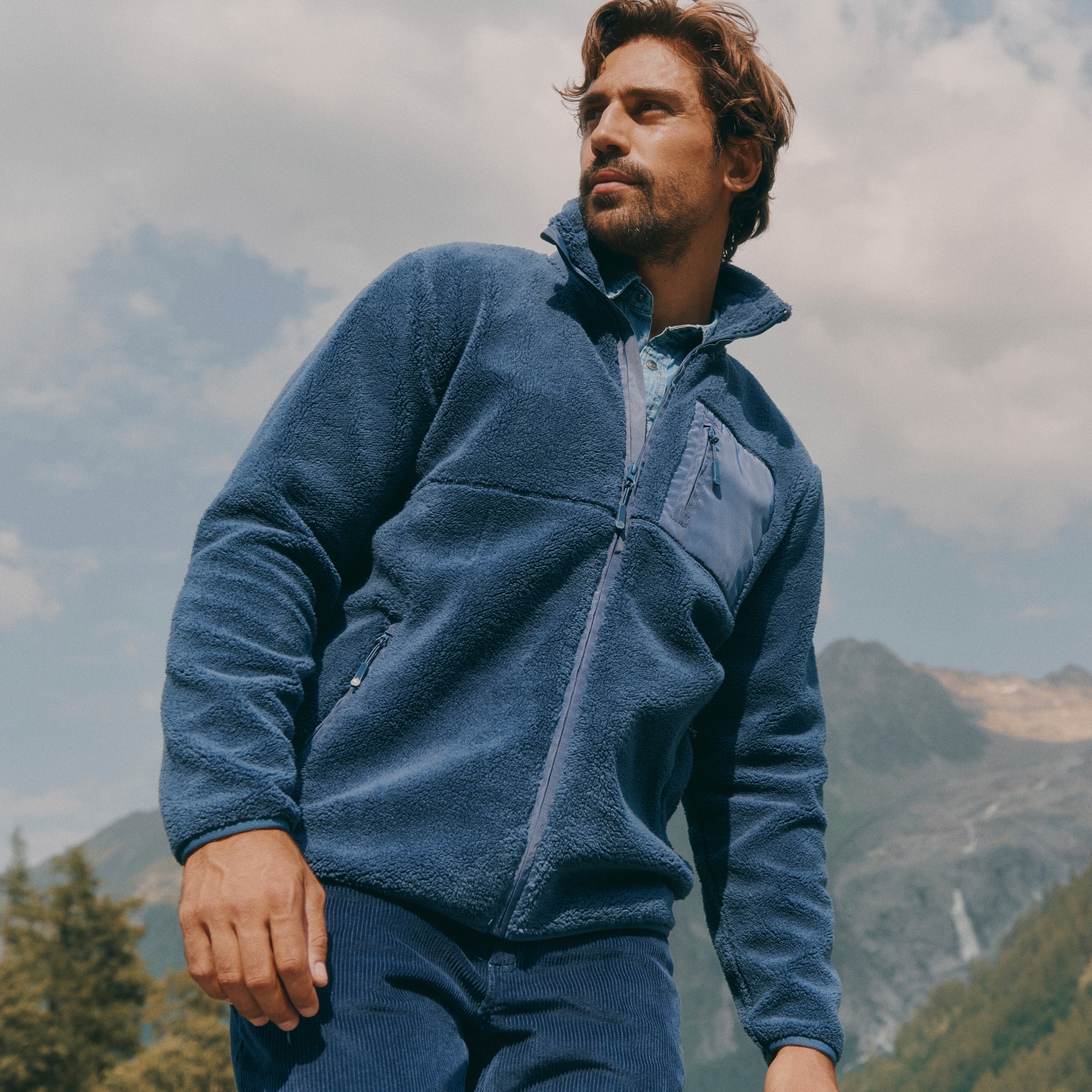 Der Mann trägt eine stylische blaue Fleecejacke und passende Cordhose.