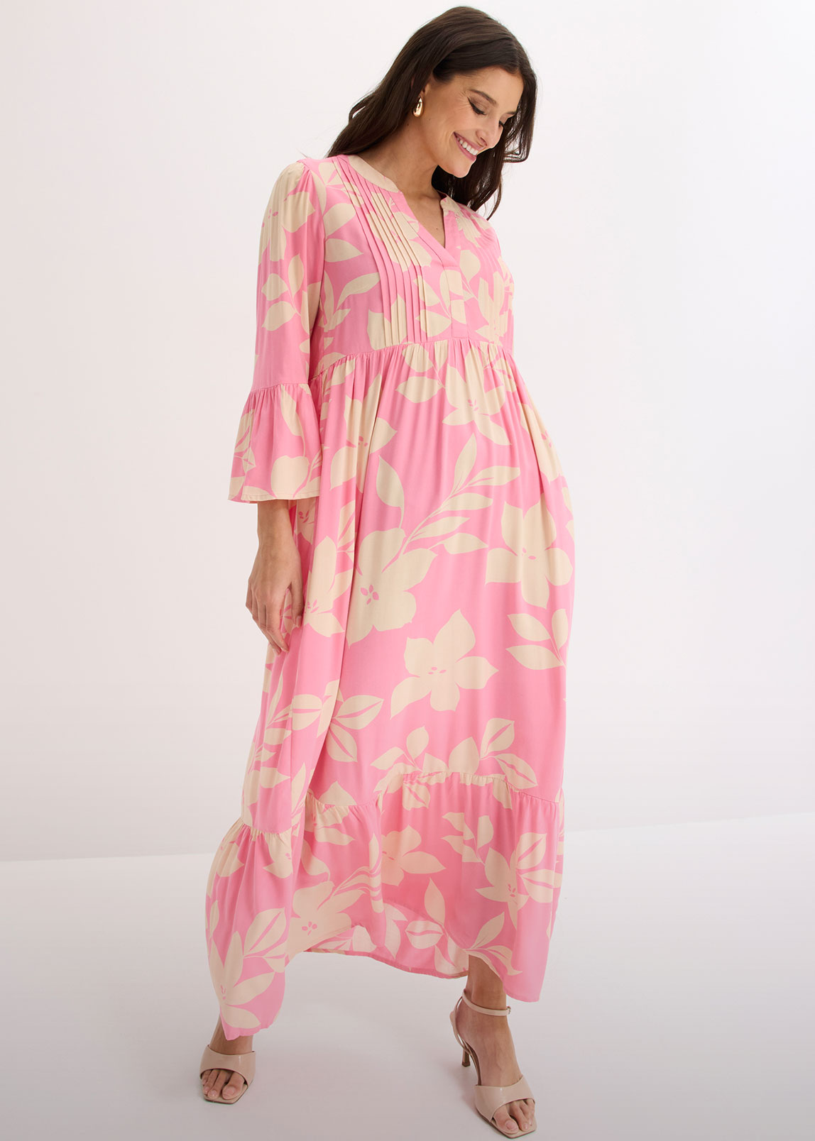 Langes, rosafarbenes Kleid mit Blumenmuster, V-Ausschnitt, Falten und weiten Ärmeln.