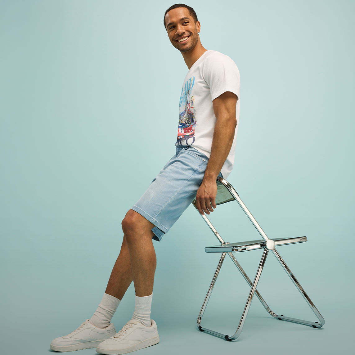 Lässiger Look mit weißem T-Shirt, hellblauen Shorts und weißen Sneakers.