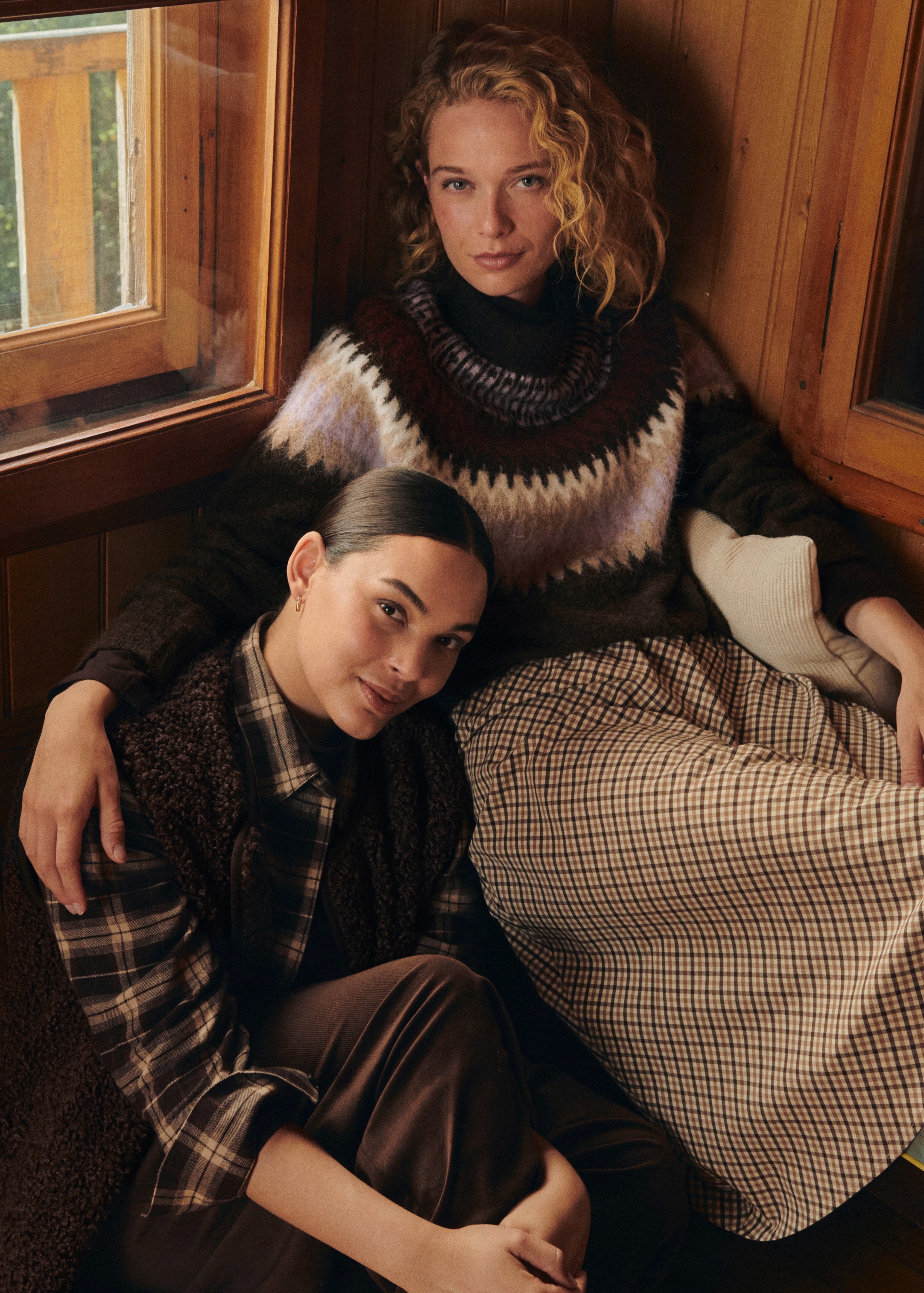 Kuschelige Mode mit Strickpullover, kariertem Rock, kariertem Hemd, Weste und brauner Hose.