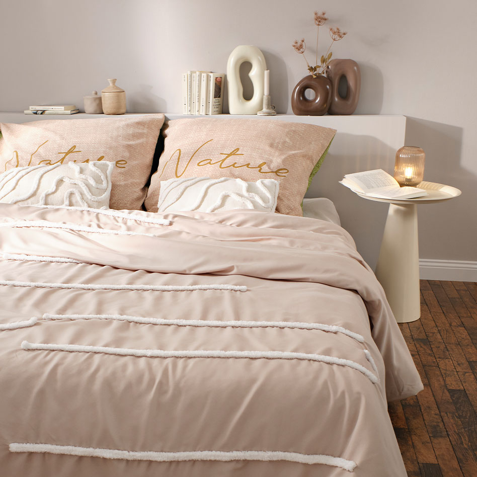 Zartrosa Bettwäsche mit feinen Streifen schmückt das gemütliche Schlafzimmer in warmen Pastelltönen.