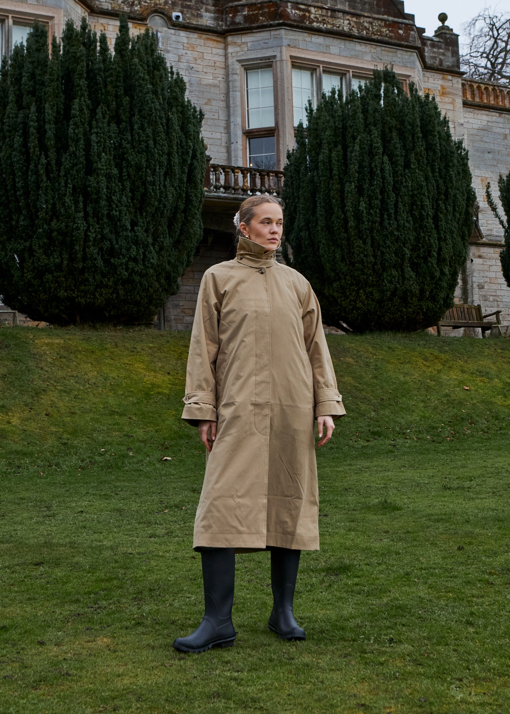 Eleganter beigefarbener Trenchcoat und Gummistiefel.