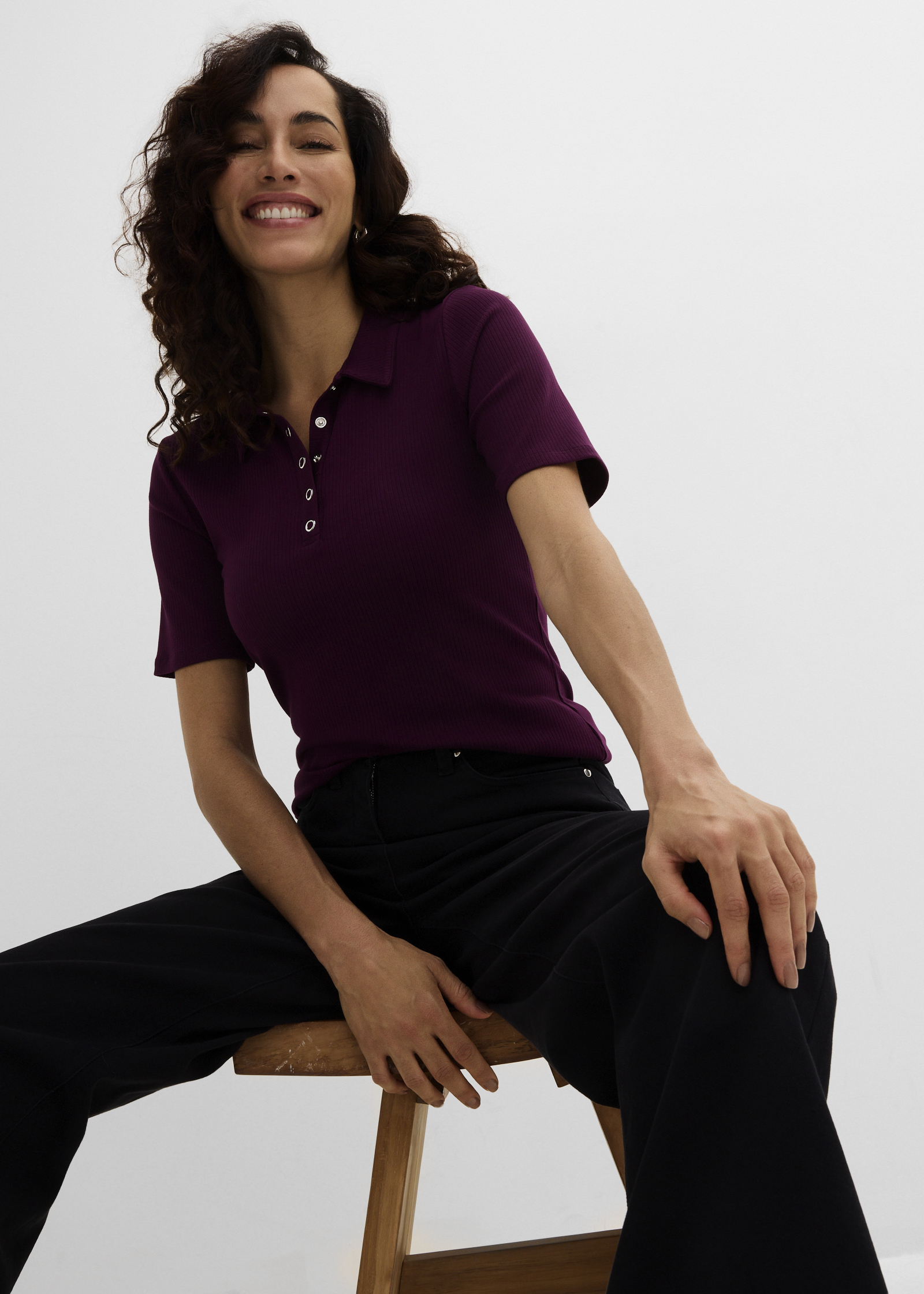 Ein bordeauxrotes Poloshirt mit Knöpfen und eine weite schwarze Hose.